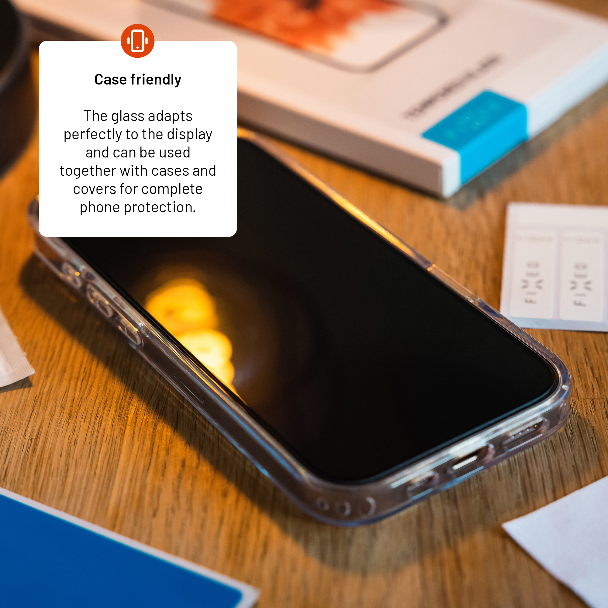 Ein Smartphone in einer Schutzhülle auf Holz mit Text über hüllenfreundlichen Glasschutz.