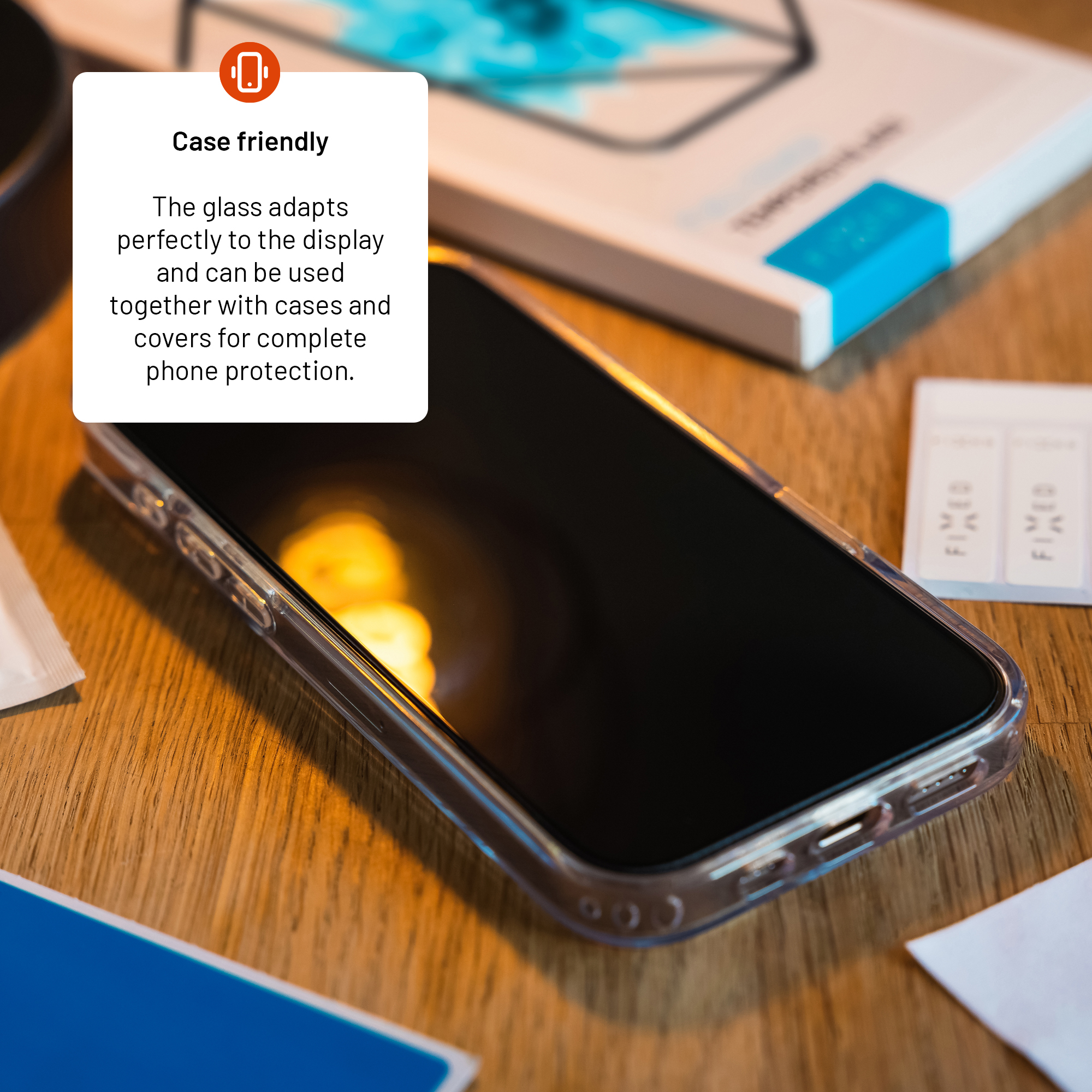 Ein Smartphone in einer klaren Hülle auf einem Holztisch, mit Verpackung und Etiketten.