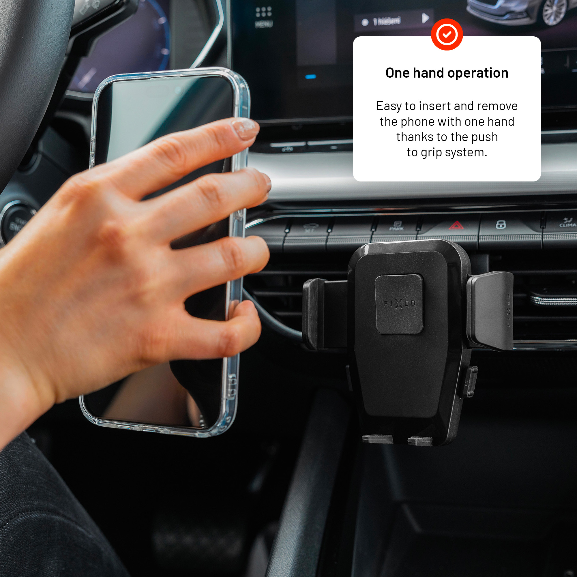 Eine Hand hält ein Telefon in der Nähe einer schwarzen Autohalterung mit Text.