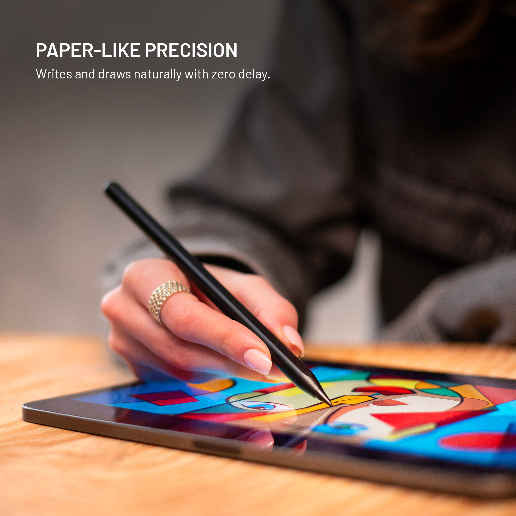 Person zeichnet mit einem digitalen Stift auf ein Tablet auf einem Holztisch.
