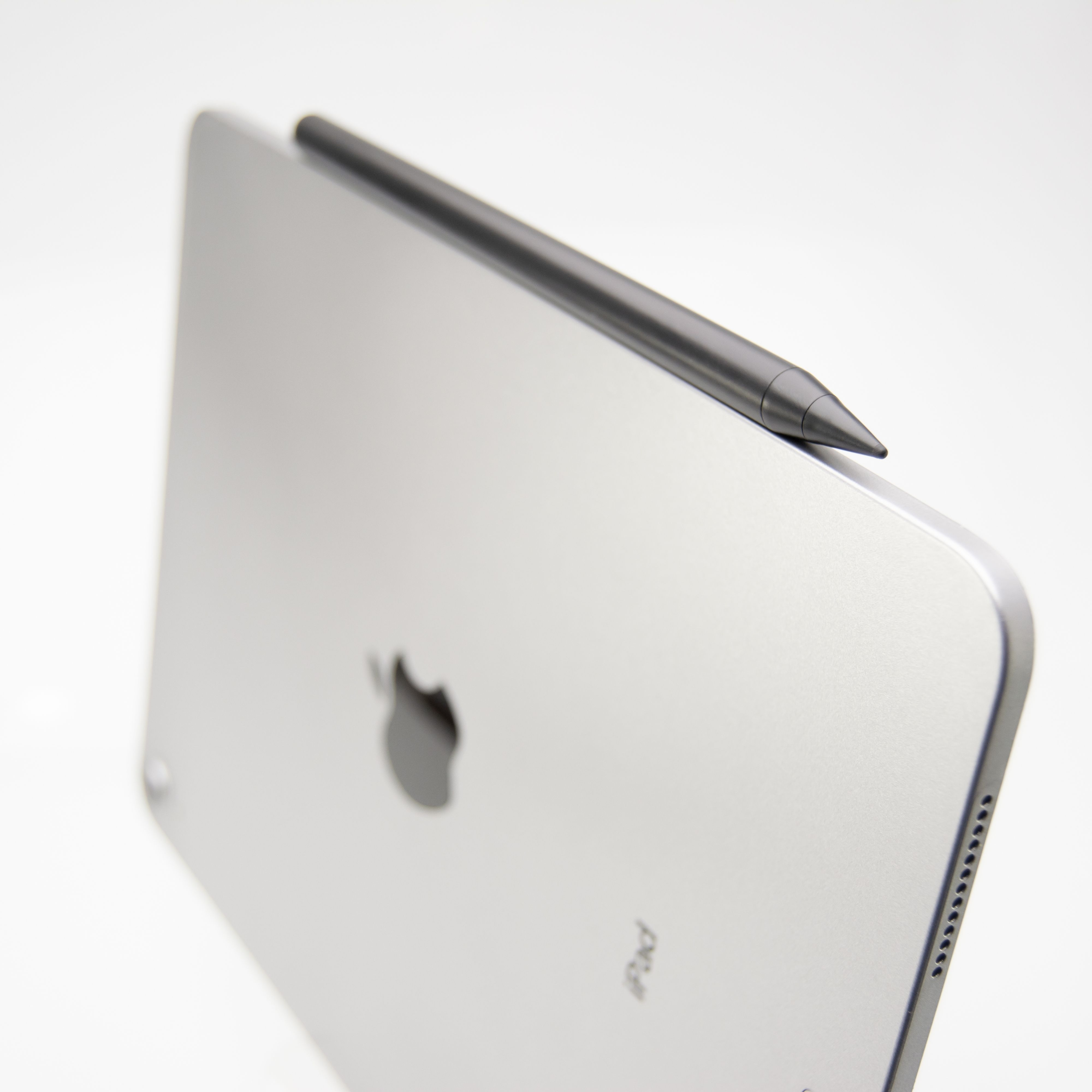 Ein silbernes iPad steht aufrecht mit einem dunklen Stift oben auf weißem Hintergrund.