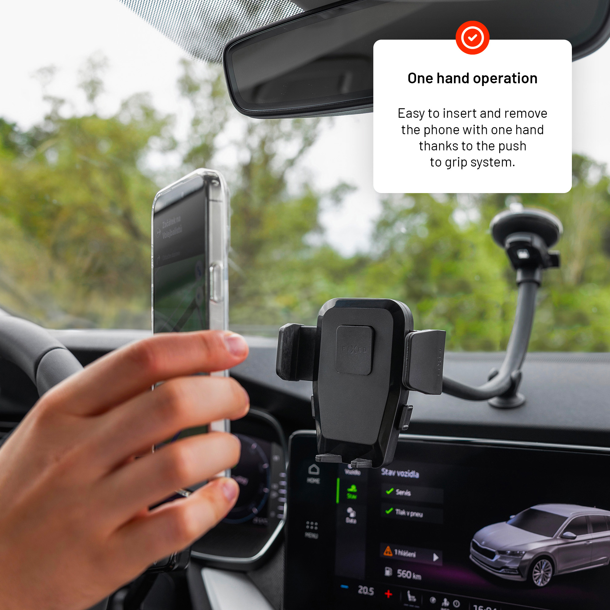 Eine Hand hält ein Smartphone neben einer Handyhalterung am Armaturenbrett, mit einem Textfeld oben.