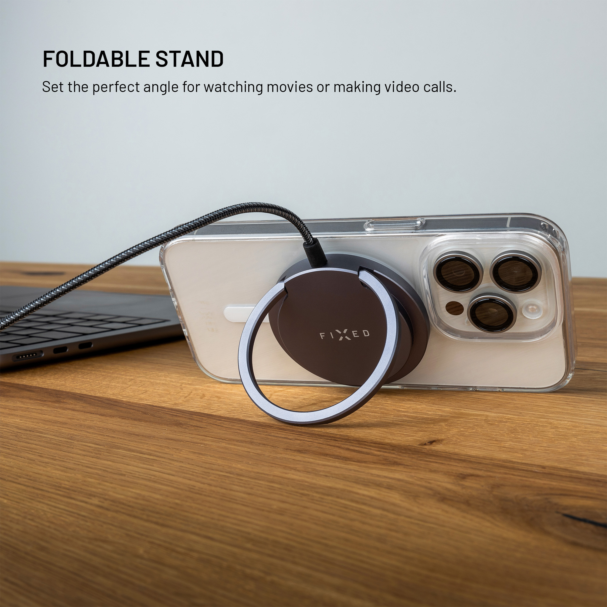 Ein faltbarer Ständer mit Ring befestigt an der Rückseite eines Smartphones auf einem Holz Tisch.