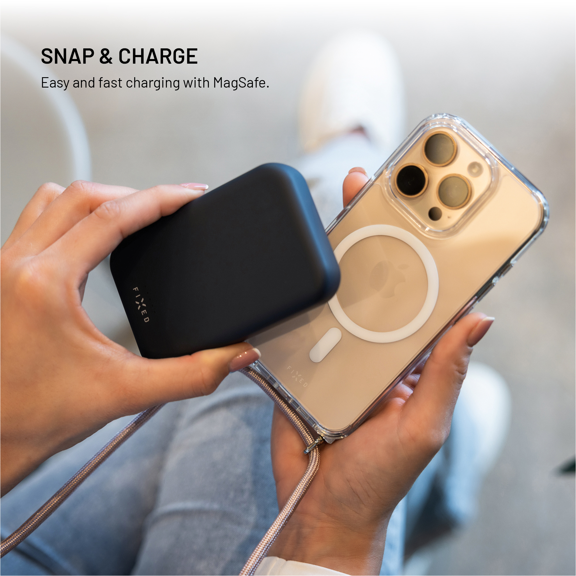 Jemand hält ein schwarzes Powerbank-Gerät und ein Smartphone mit klarer Hülle in der Hand.