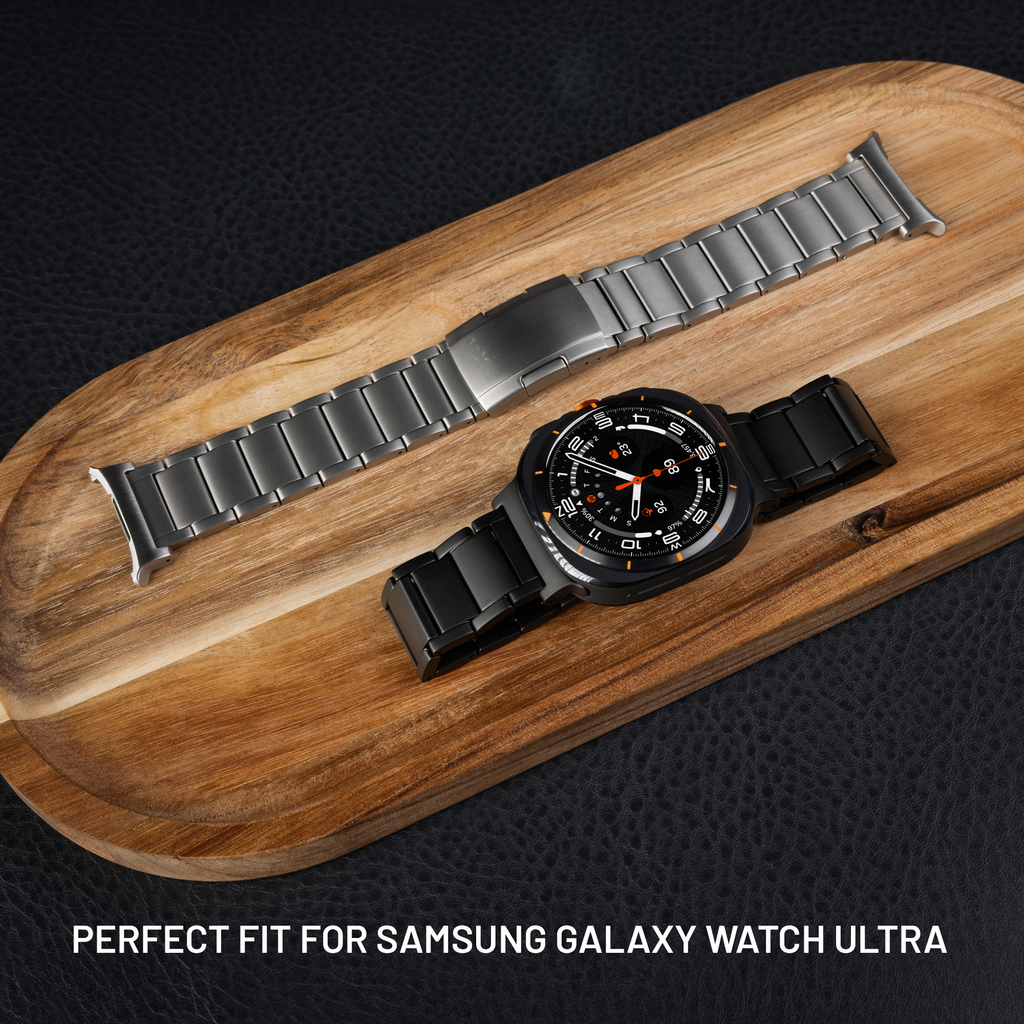 Eine schwarze Samsung Galaxy Watch Ultra und ein silbernes Metallarmband auf einem Holztablett.