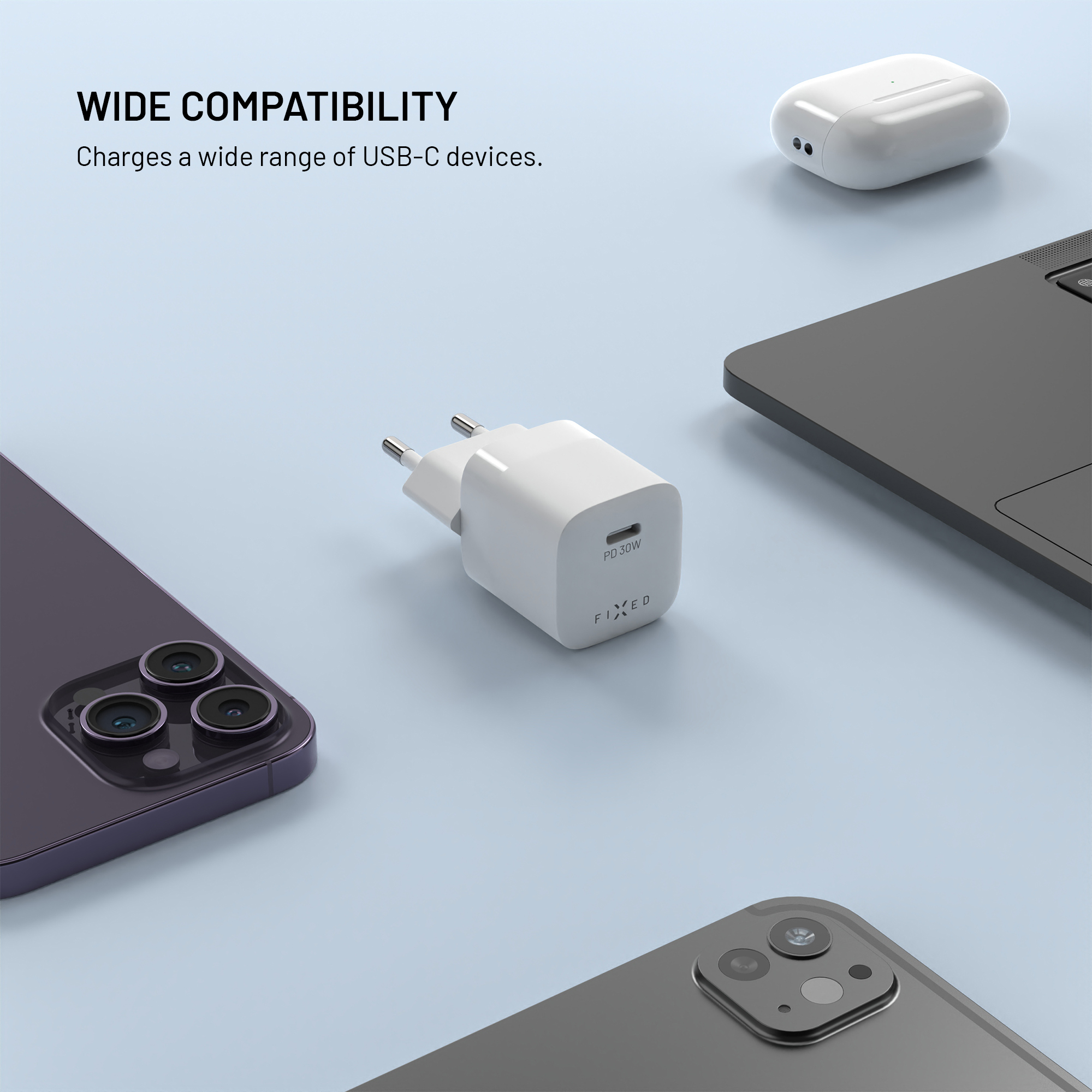 Ein weißes USB-C-Ladegerät im Zentrum, umgeben von einem Smartphone, Ohrhörern und einem Laptop.