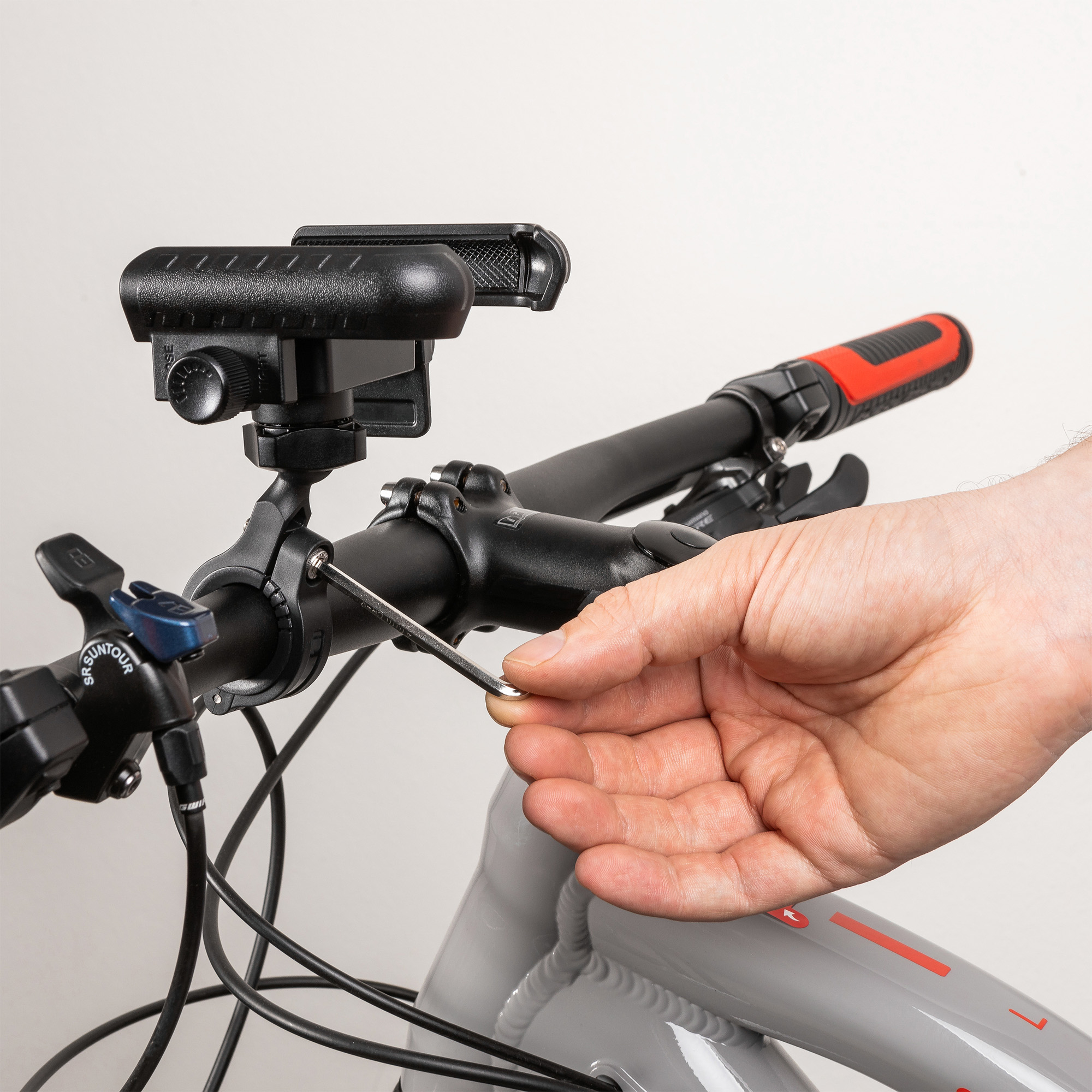 Eine Hand nutzt einen Inbusschlüssel, um eine Halterung am Fahrradlenker zu befestigen.