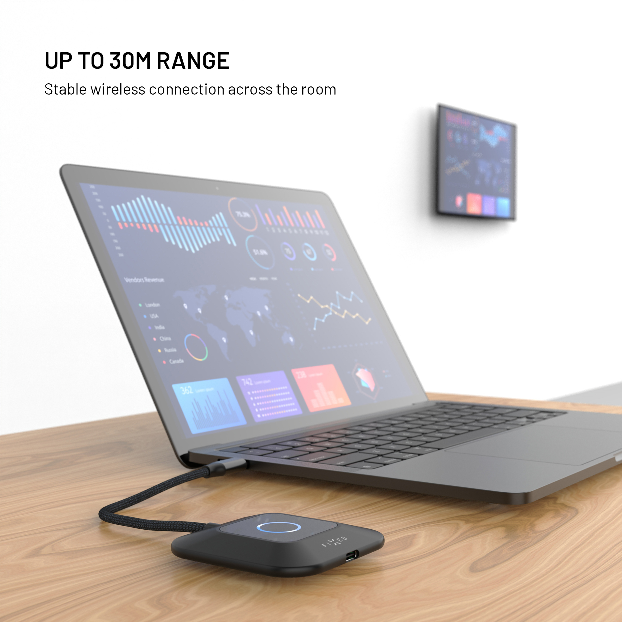 Ein schwarzes Laptop und ein kleiner Hub stehen auf einem Holztisch vor einer weißen Wand.
