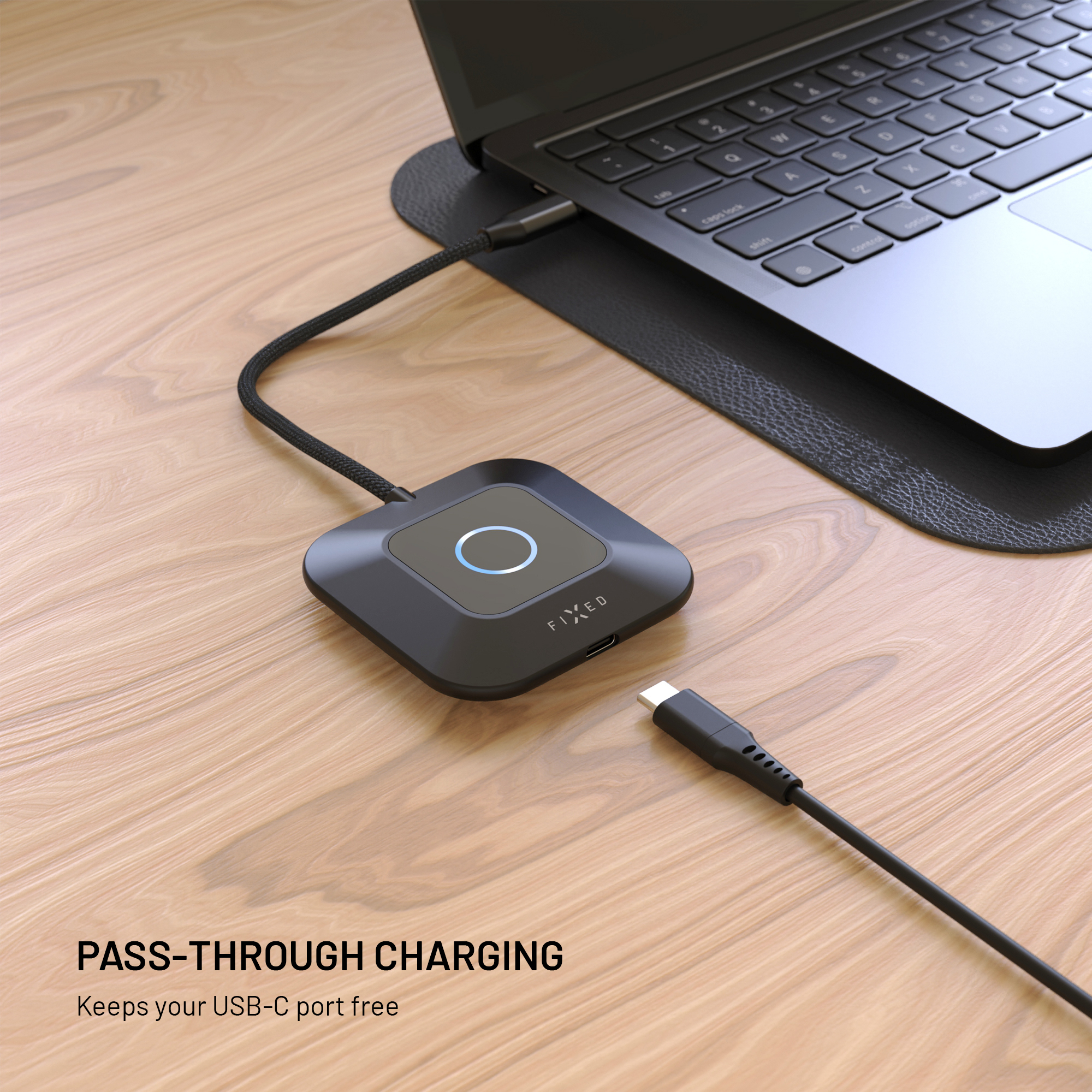 Ein schwarzer USB-C Hub mit Leuchtring liegt auf Holz, verbunden mit einem Laptop und einem Kabel.
