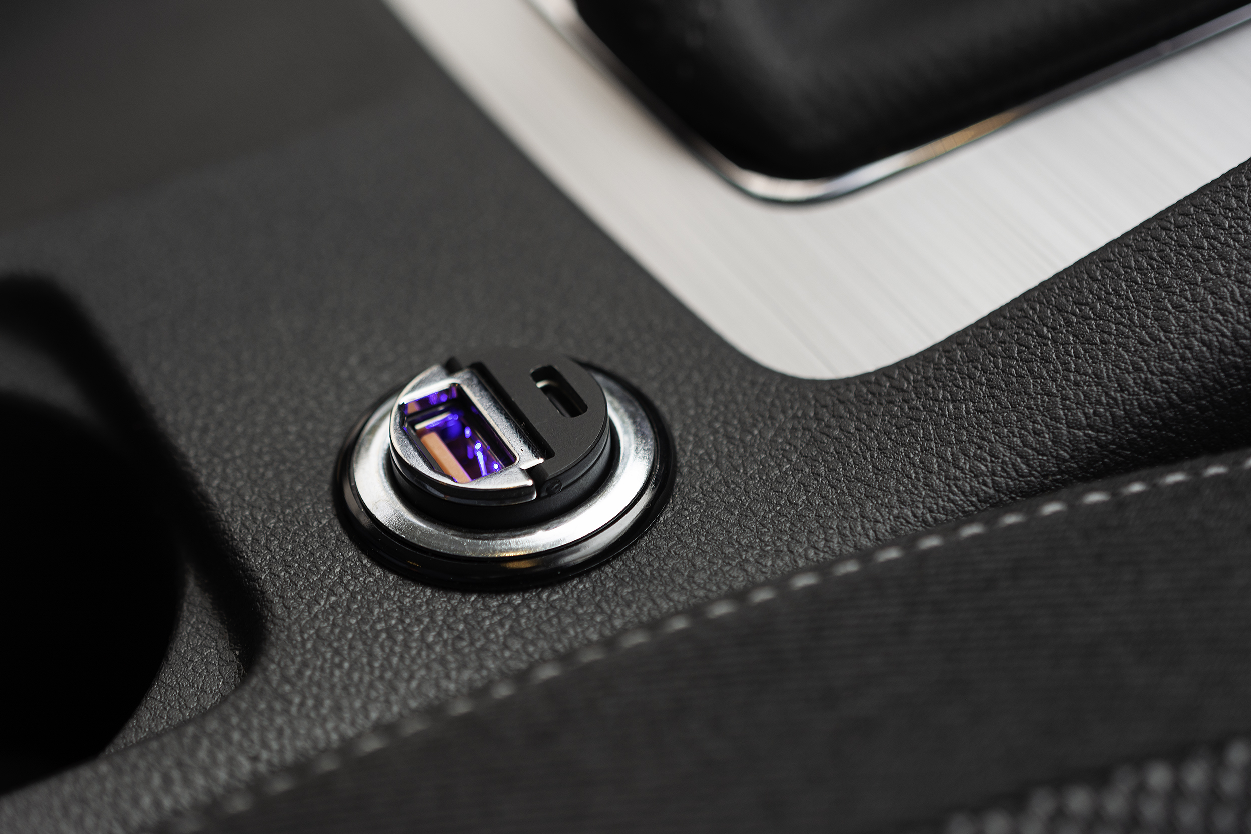 Ein Autoinnenraum-Detail zeigt einen beleuchteten USB-Anschluss und USB-C-Lader in der Konsole.