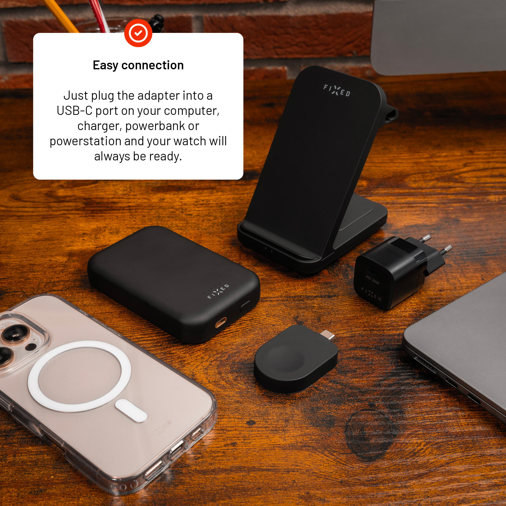 Schwarzes Ladezubehör wie Powerbank, Ständer und kleiner Stecker auf Holz.