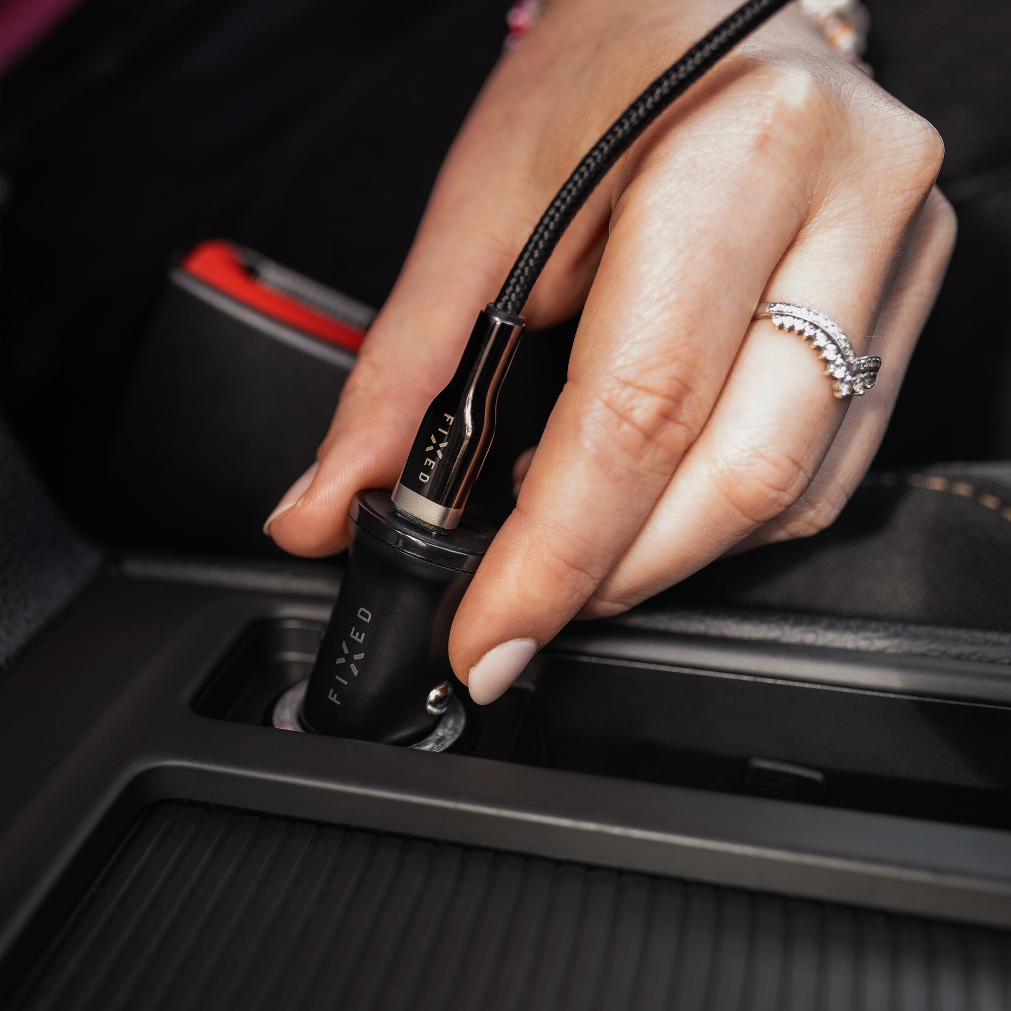 Eine Hand steckt ein schwarzes Fixed-Autoladegerät in eine Fahrzeugsteckdose.