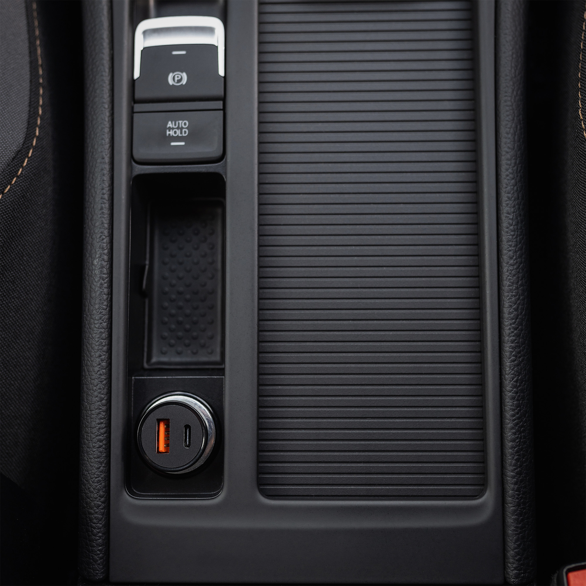 Innenraum der Autokonsole mit elektronischer Feststellbremse, Auto-Hold-Taste, kleinem Fach und USB-Anschlüssen.