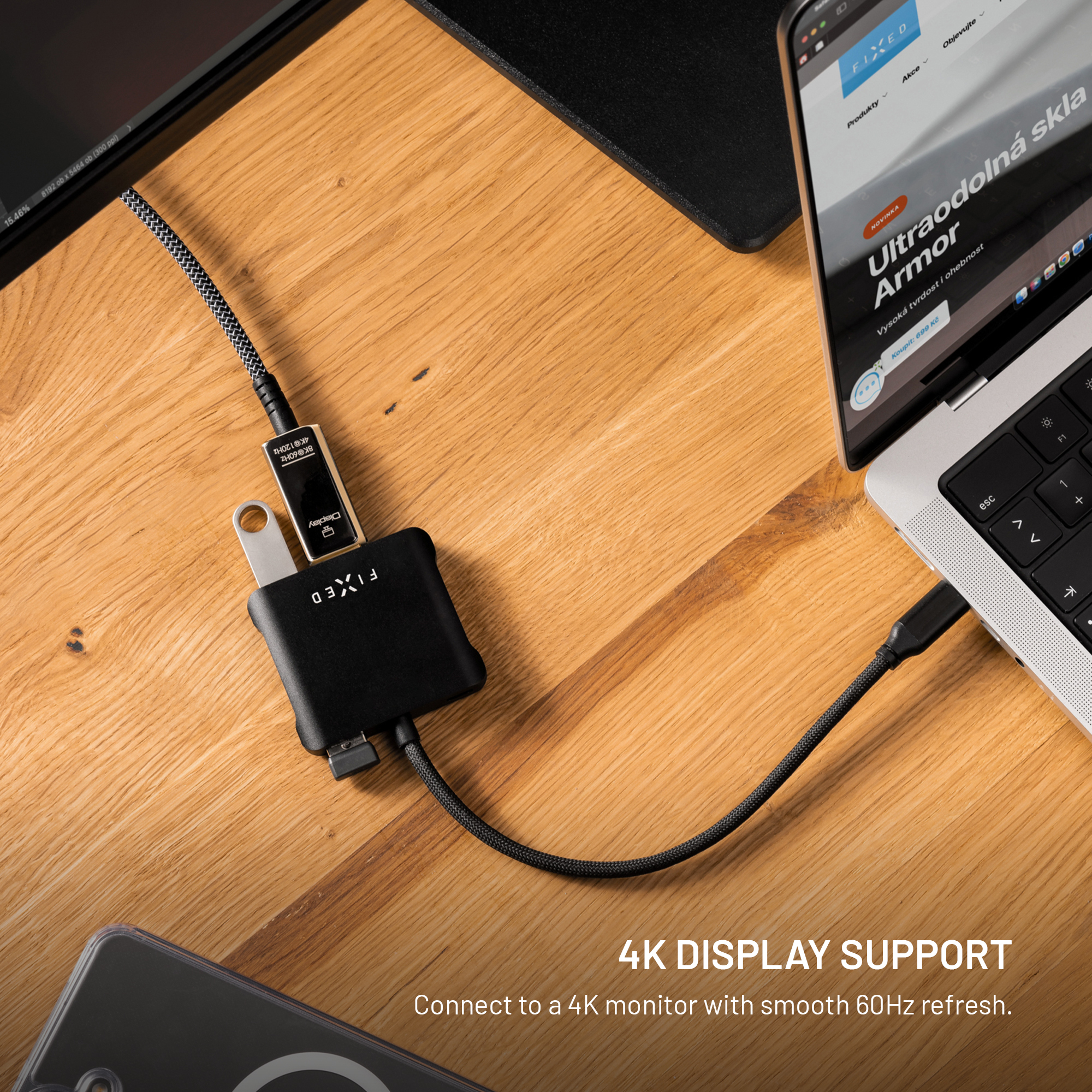 Ein schwarzer USB-C-Hub liegt auf einem Holzschreibtisch, verbunden mit einem Laptop und einem Kabel.