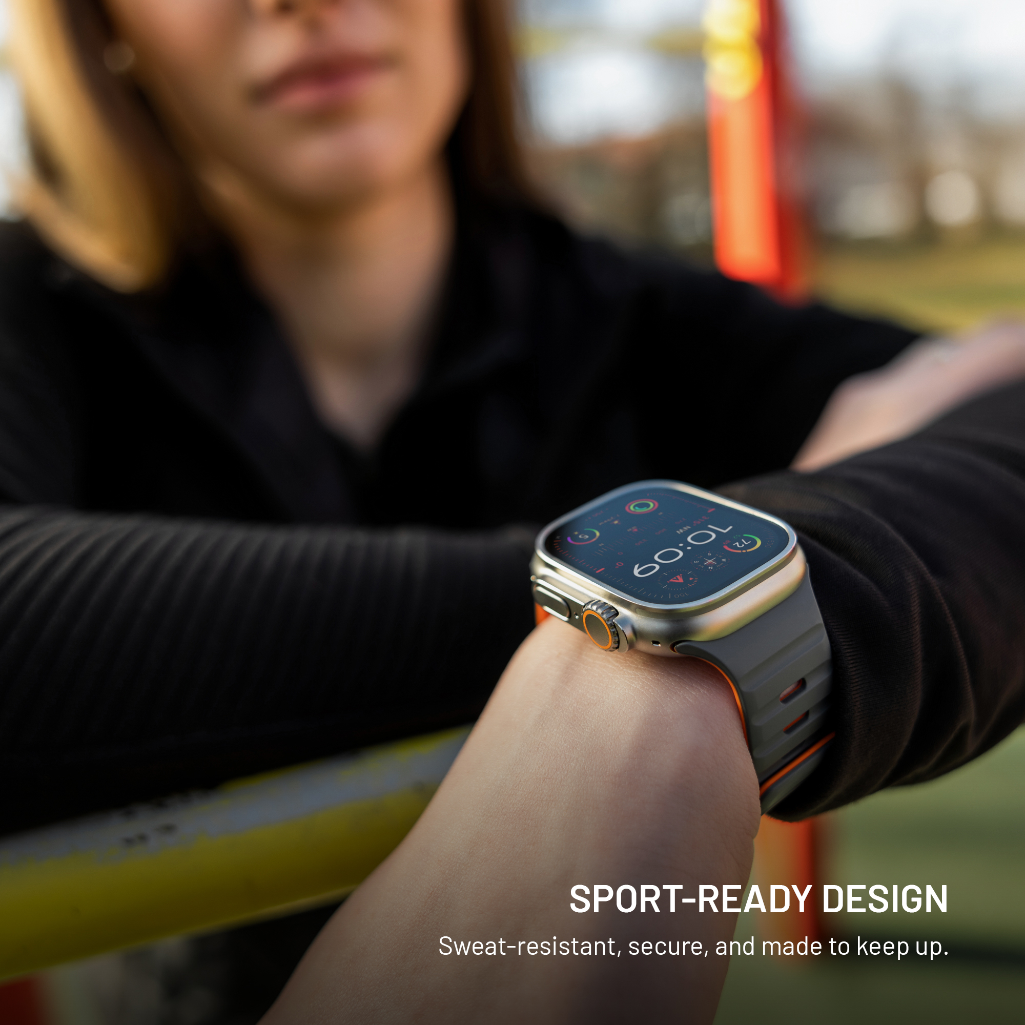 Una persona lleva un reloj inteligente deportivo con correa gris y esfera digital al aire libre.