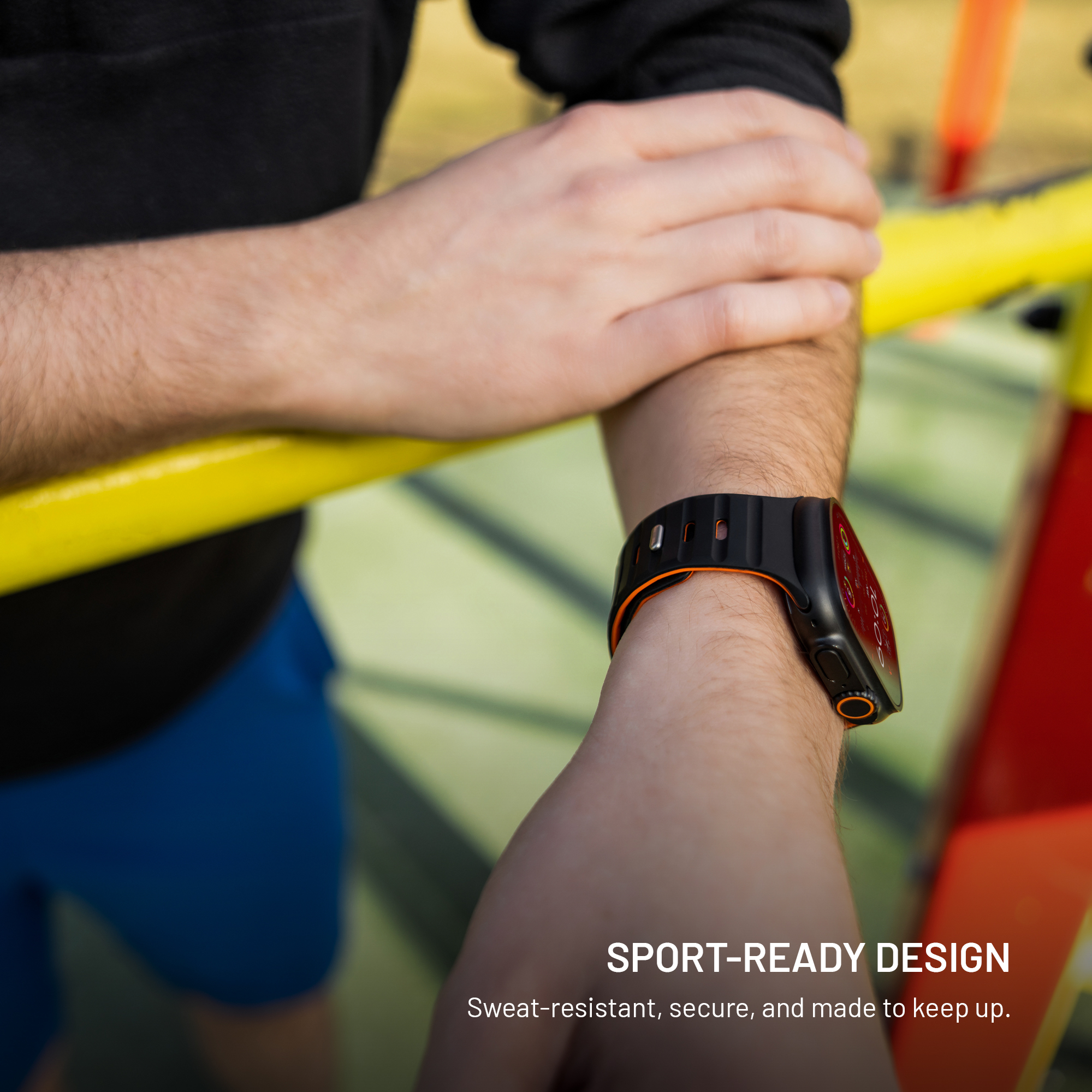 Un hombre lleva un reloj deportivo inteligente negro y naranja en su muñeca al aire libre.