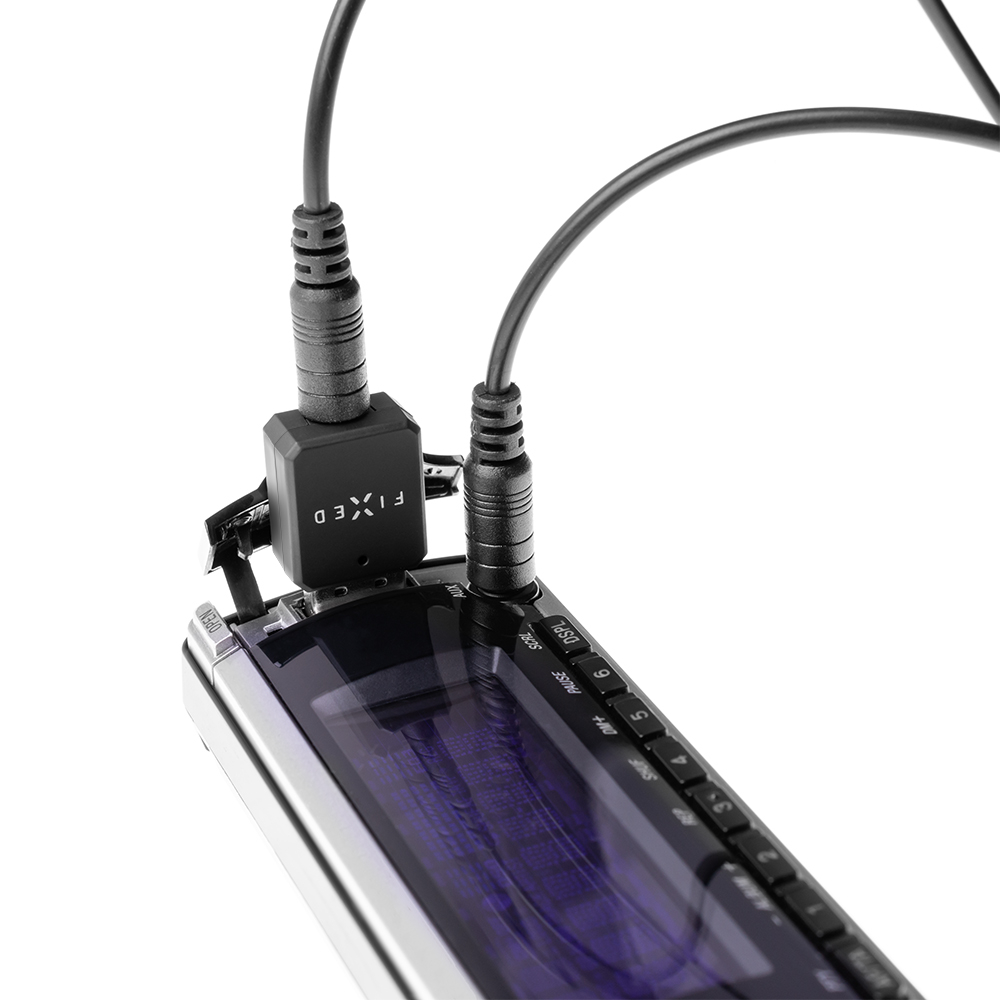Ein schwarzer Adapter und ein Audiokabel sind an ein Car-Audio-Gerät angeschlossen.