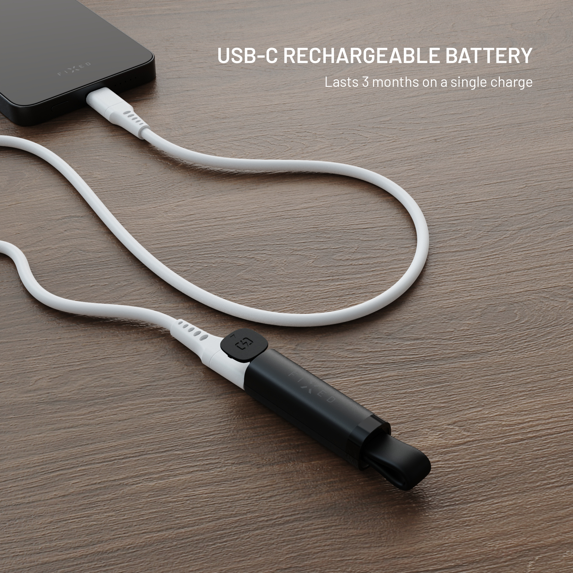 Ein weißes USB-C-Kabel verbindet ein schwarzes Gerät auf einer Holzoberfläche mit Text über eine wiederaufladbare Batterie.