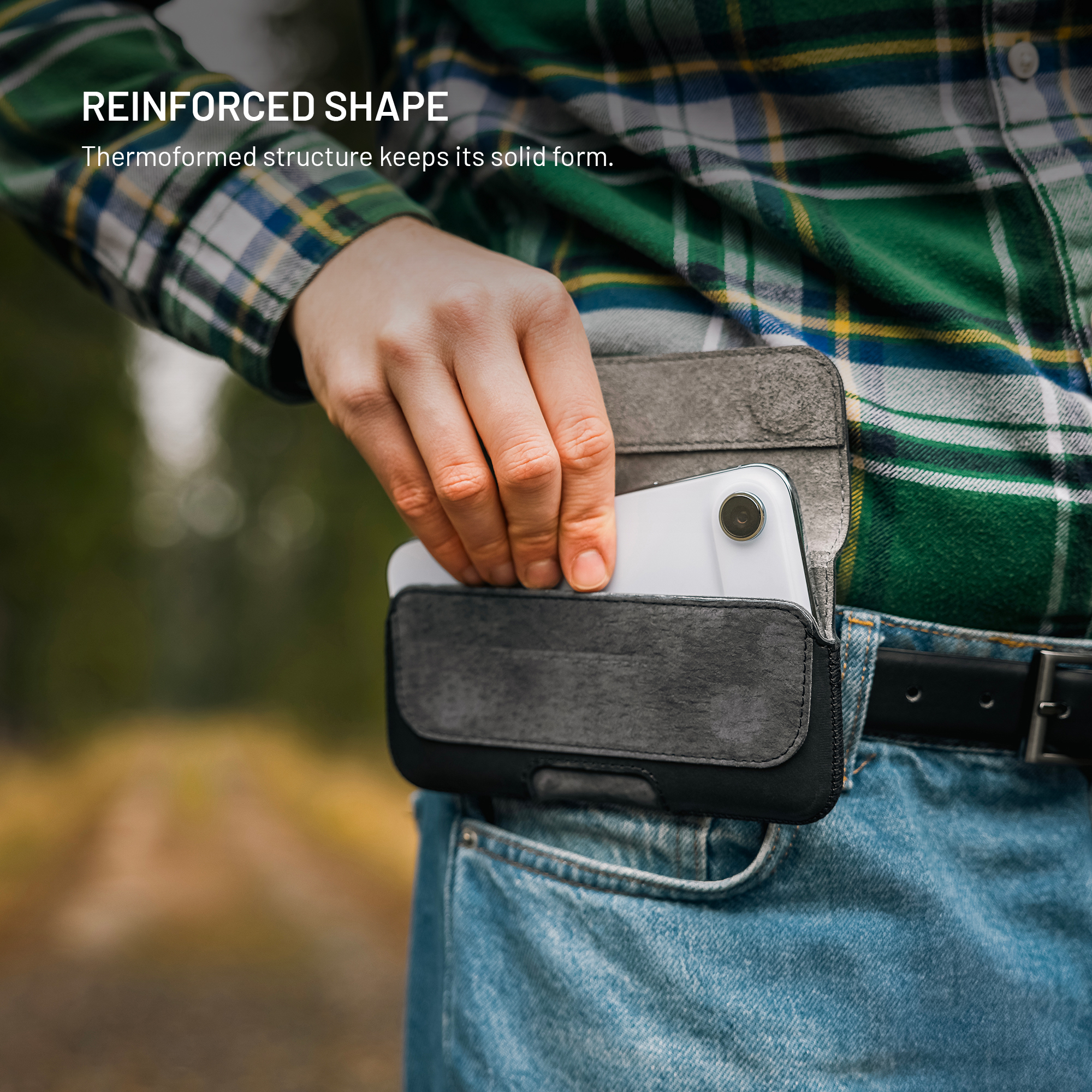 Person nimmt ein Smartphone aus einer grauen Ledertasche am Gürtel, im Hintergrund ein Wald.