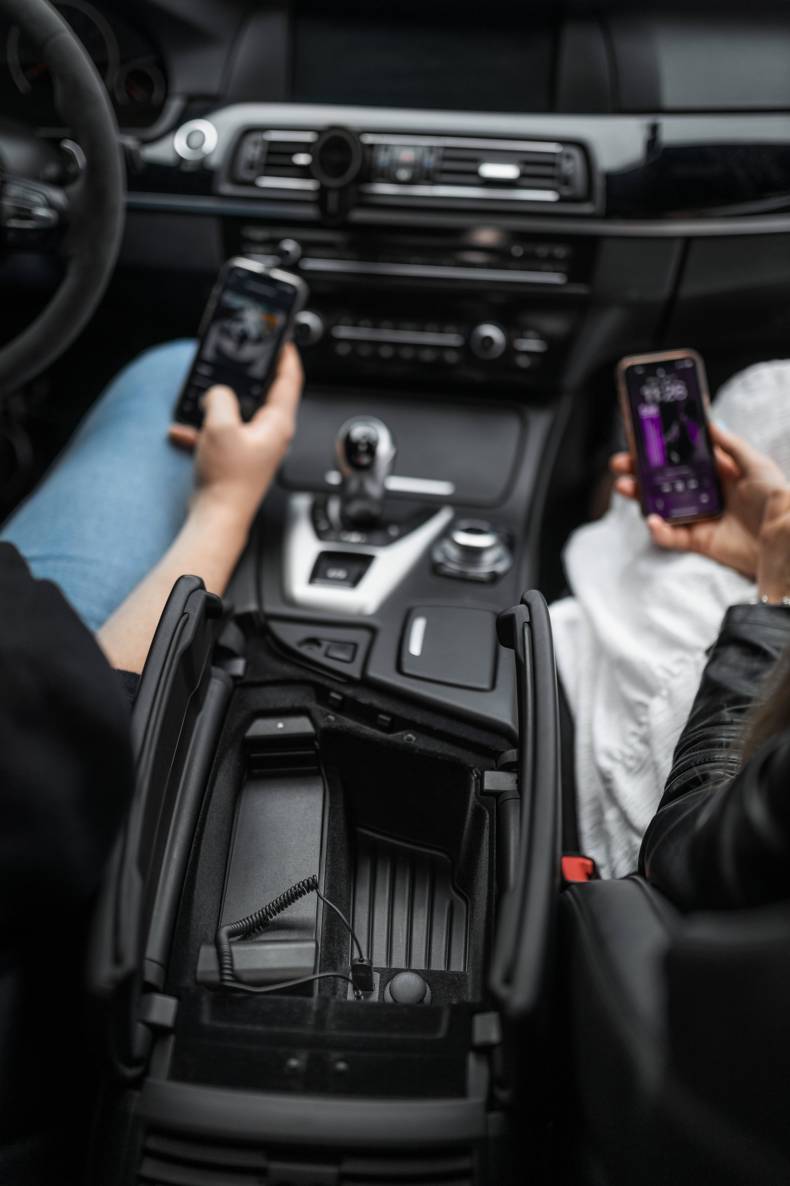 Zwei Personen sitzen in einem Auto und halten jeweils ein Smartphone in der Hand.