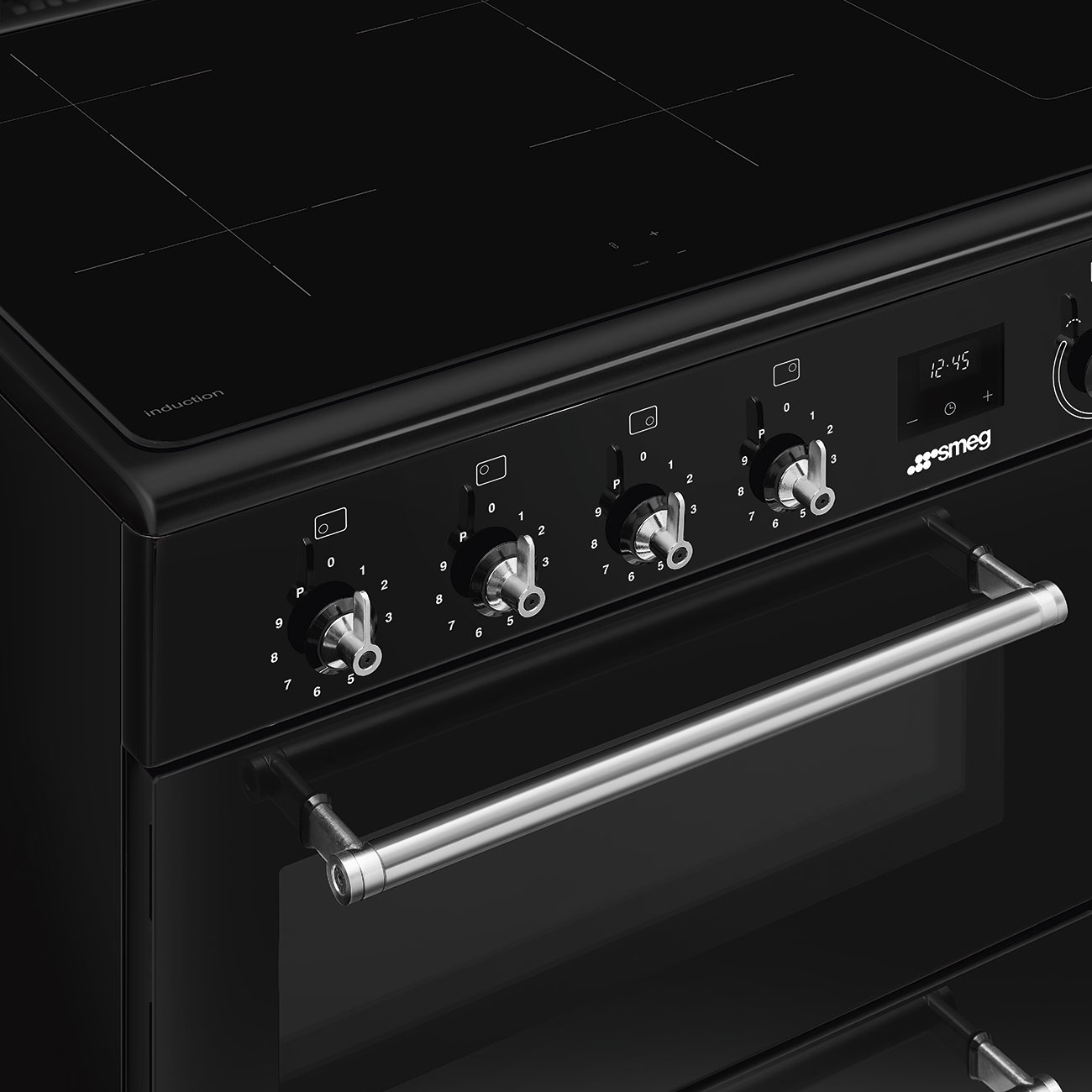 Cucina a induzione Smeg nera con manopole di controllo in metallo e un forno con maniglia in acciaio inossidabile.