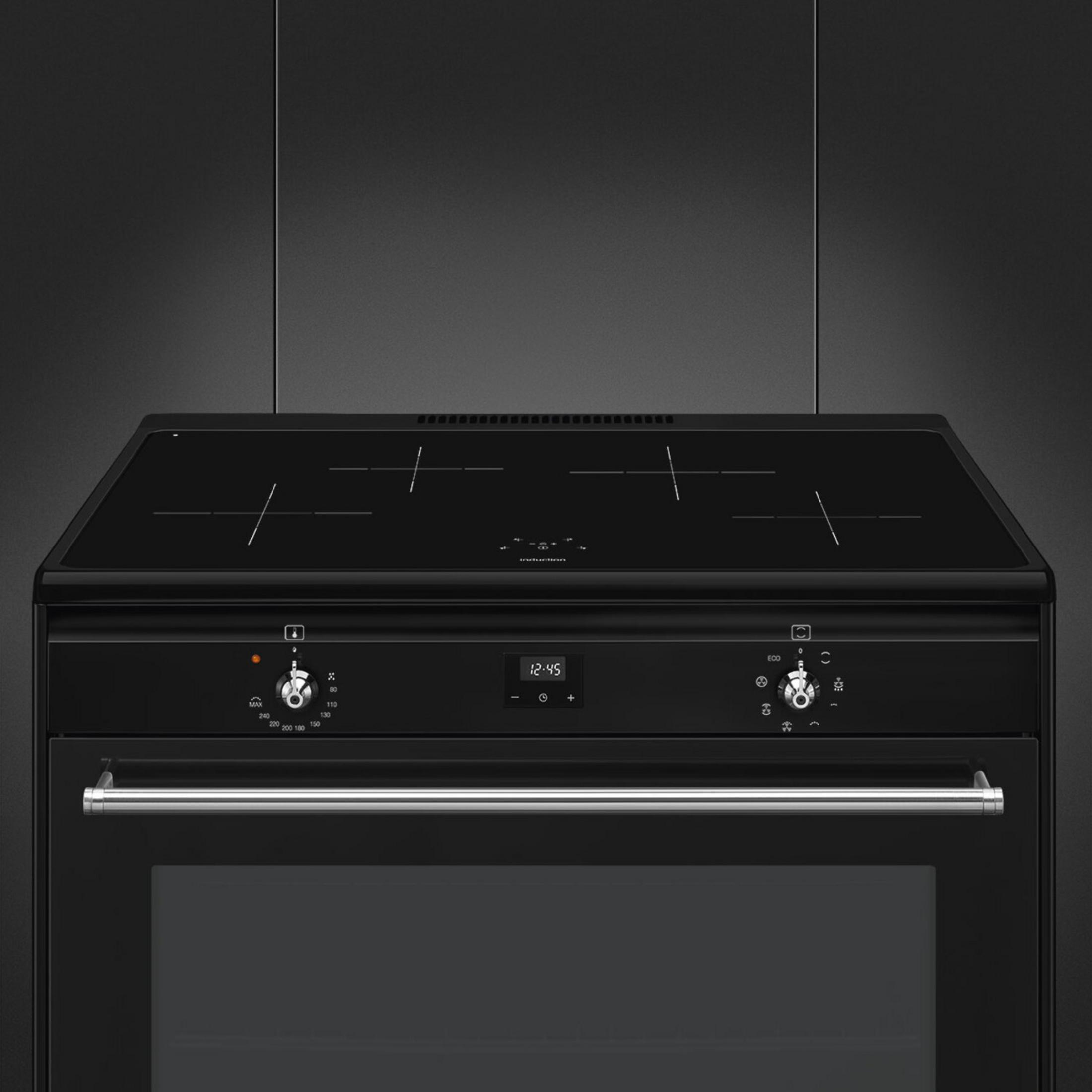 Una moderna cucina a induzione nera con manopole argentate, orologio digitale e un forno grande su parete scura.