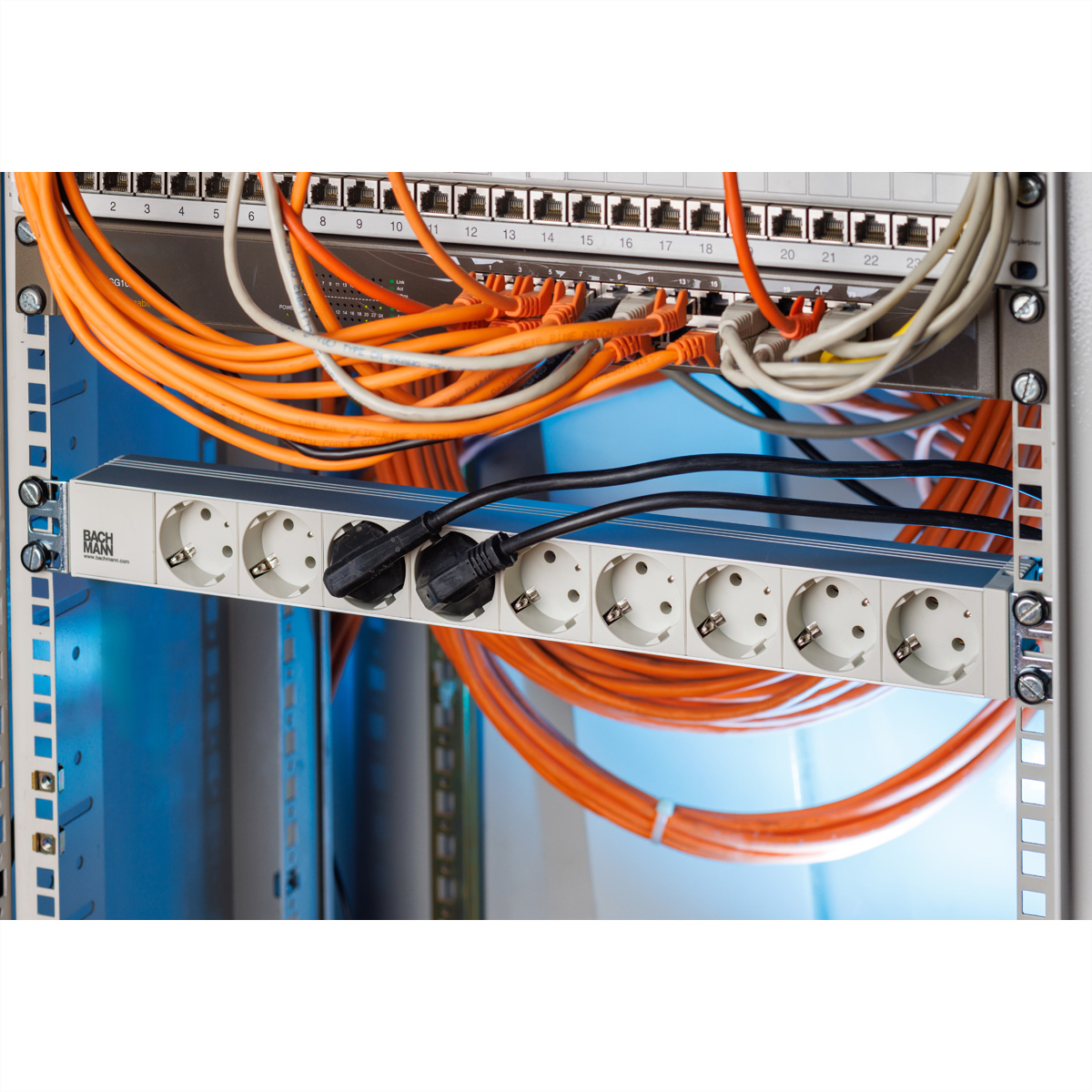 Eine Netzwerkleiste mit Steckdosen und verbundenen Kabeln in einem Serverschrank.