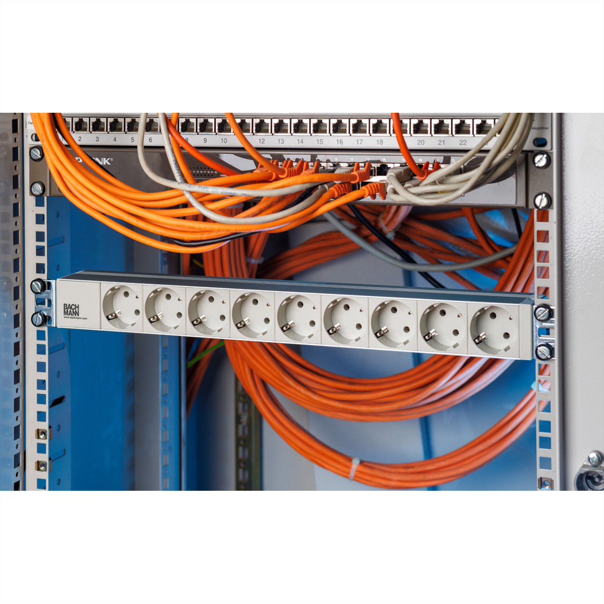 Server-Rack mit verbundenen orangen Kabeln und einer Bachmann-Steckdosenleiste.