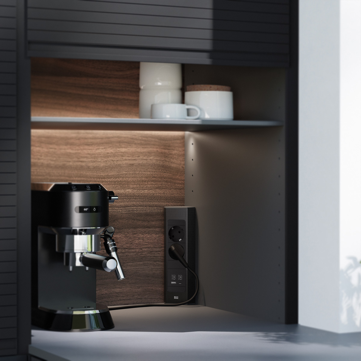 Une machine à espresso noire se trouve dans un meuble de cuisine éclairé près d'une prise et d'étagères.