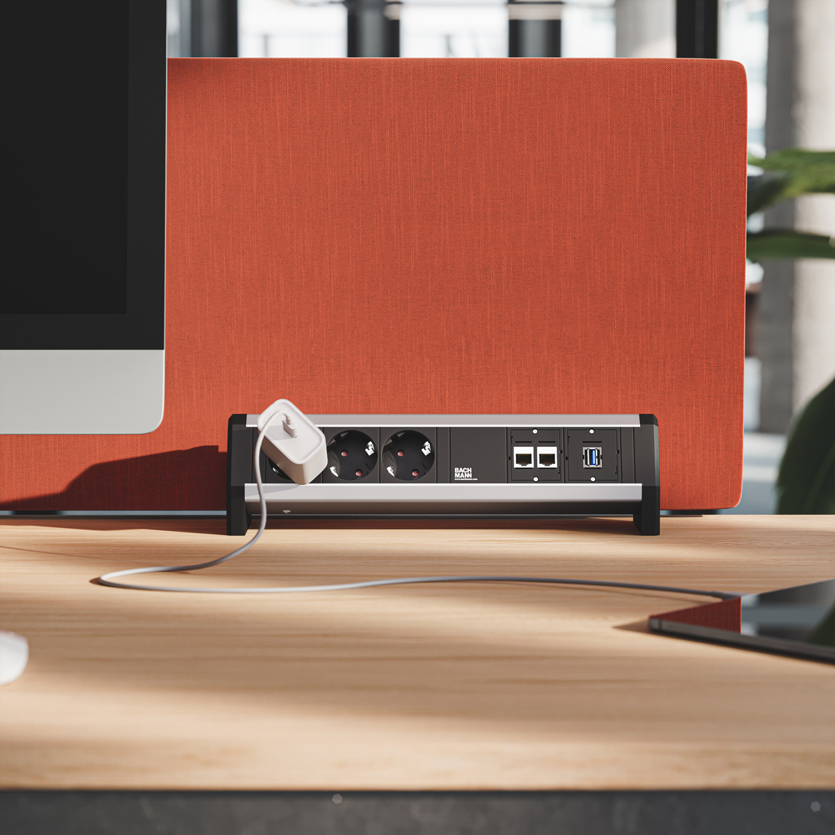 Eine Steckerleiste mit Steckdosen und USB-Anschlüssen auf einem Holztisch vor einer orangefarbenen Trennwand.