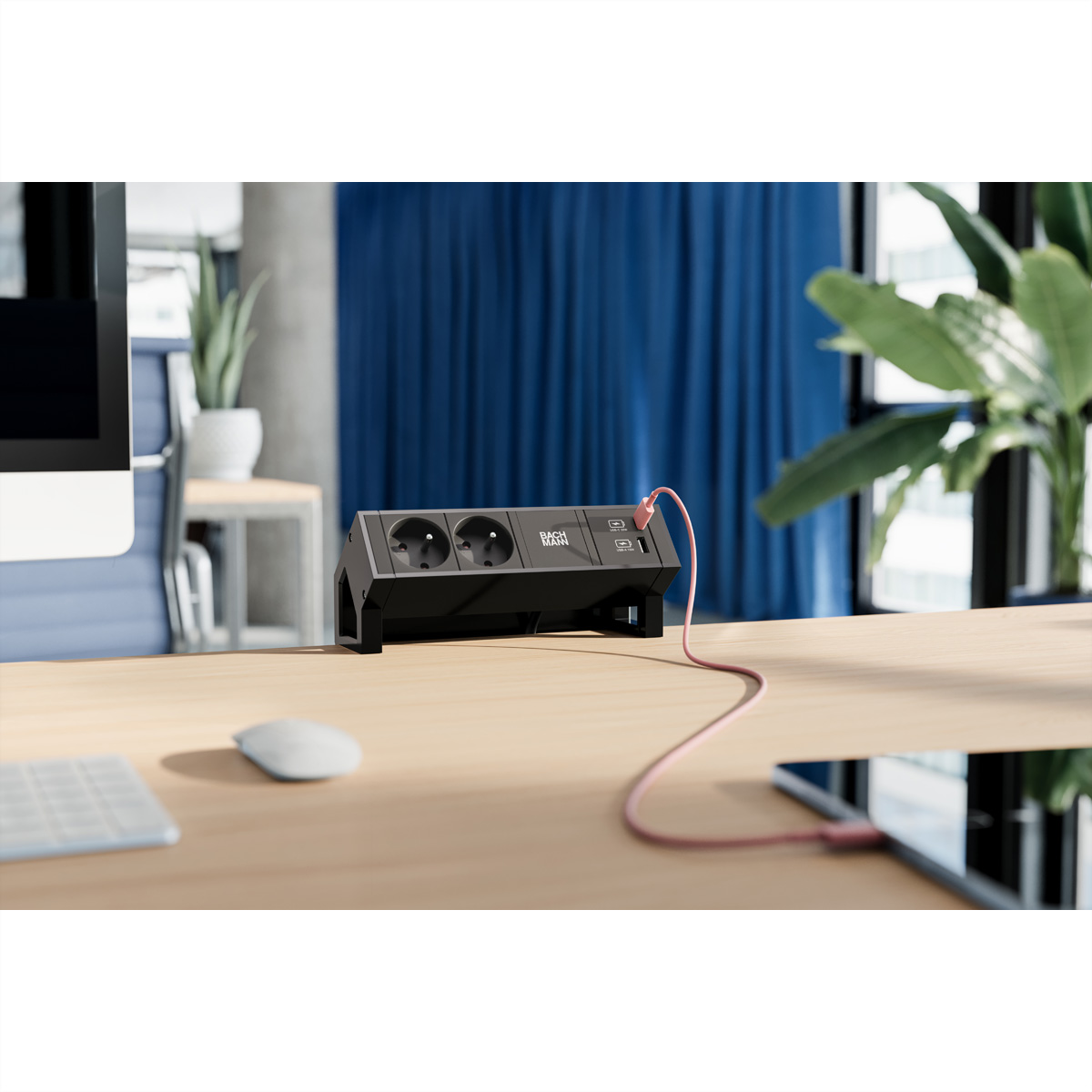Black desk power strip with USB ports on a wooden desk, connected to a tablet.