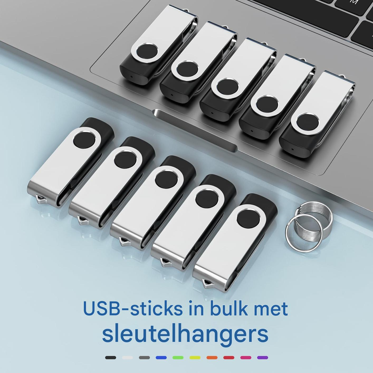 Mehrere USB-Sticks mit silberner Kappe und Schlüsselringen vor einem Laptop.