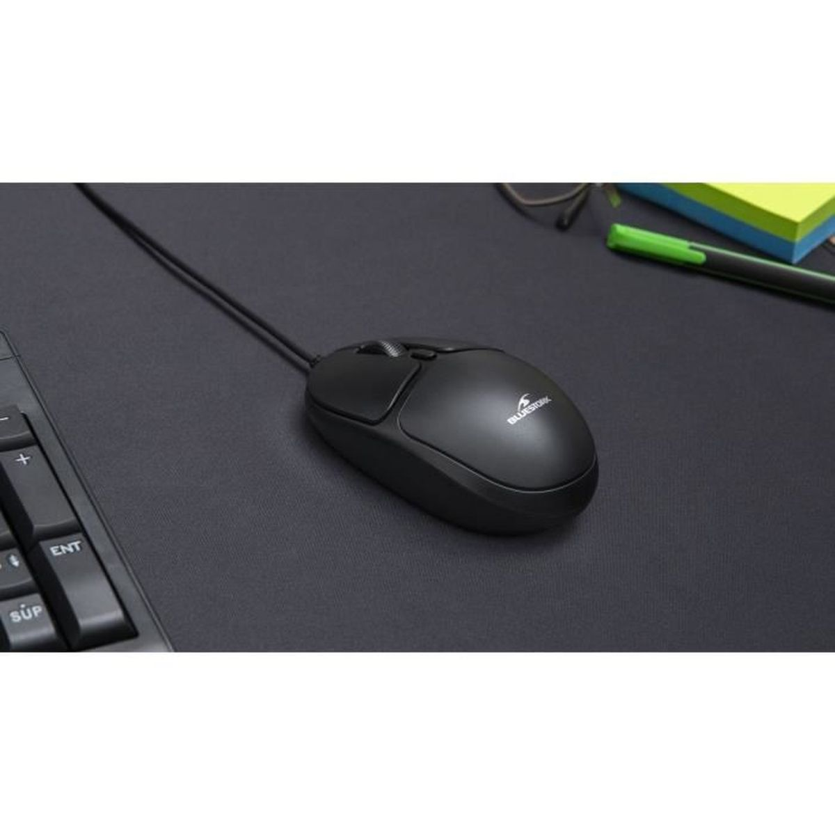 Un ratón de ordenador con cable negro en un escritorio oscuro.