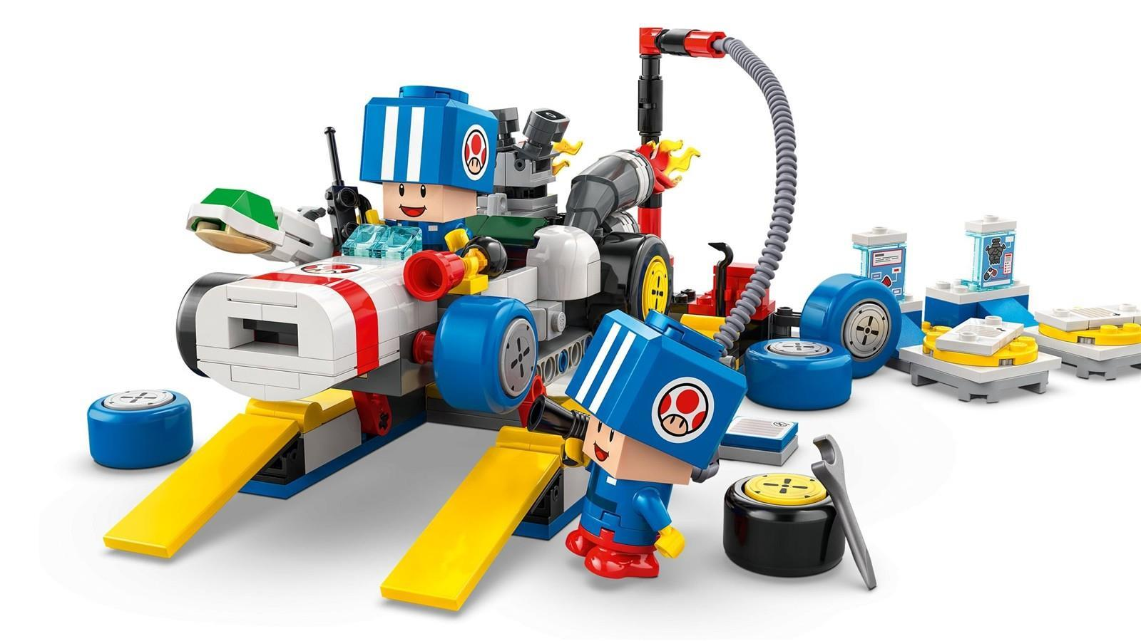 Vehículo Lego con ruedas azules, figura de Toad conduciendo y accesorios de taller.