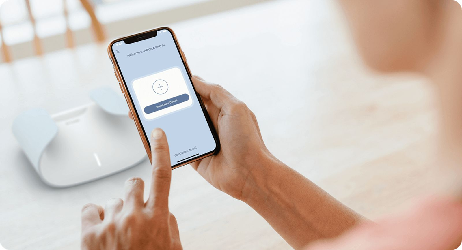 Una persona usa una app de smartphone para configurar un router inalámabrico blanco en una mesa.