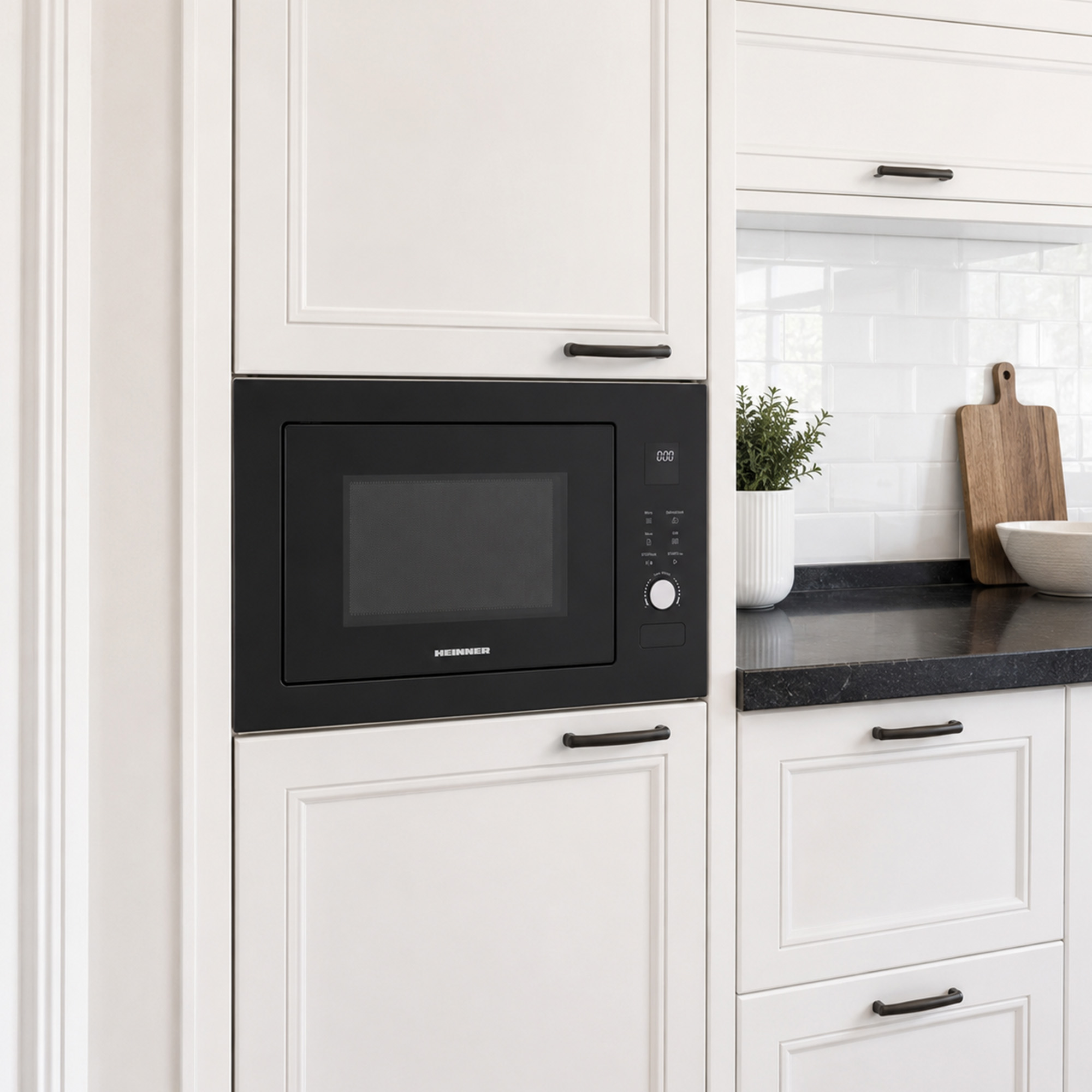 Built-in black microwave in a white kitchen with a dark countertop and decorative items.