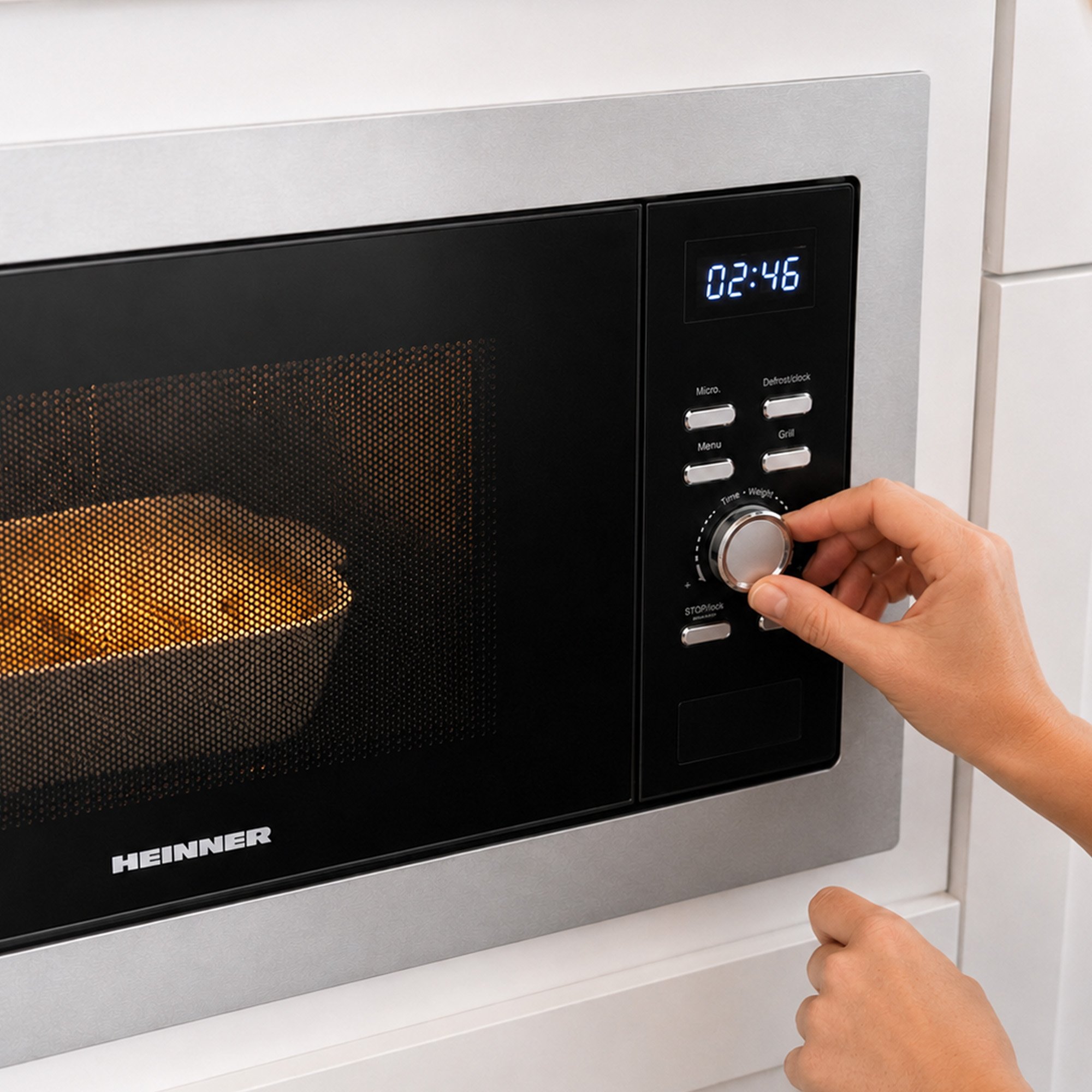 A hand adjusts the timer dial on a modern built-in microwave oven.
