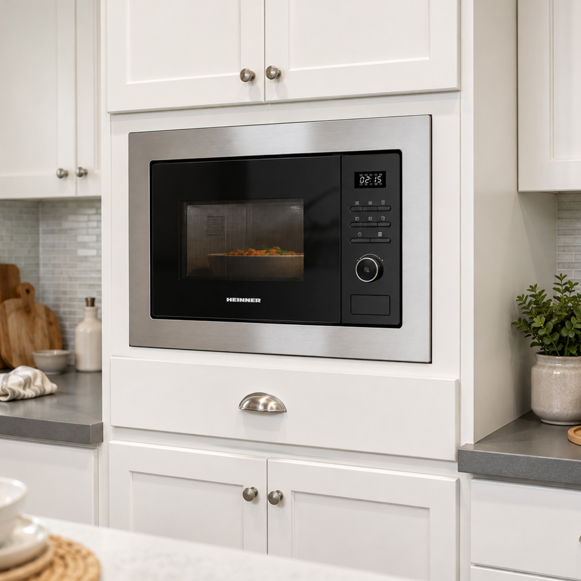 A stainless steel built-in microwave sits in a white kitchen cabinet, featuring digital controls and a glass door.
