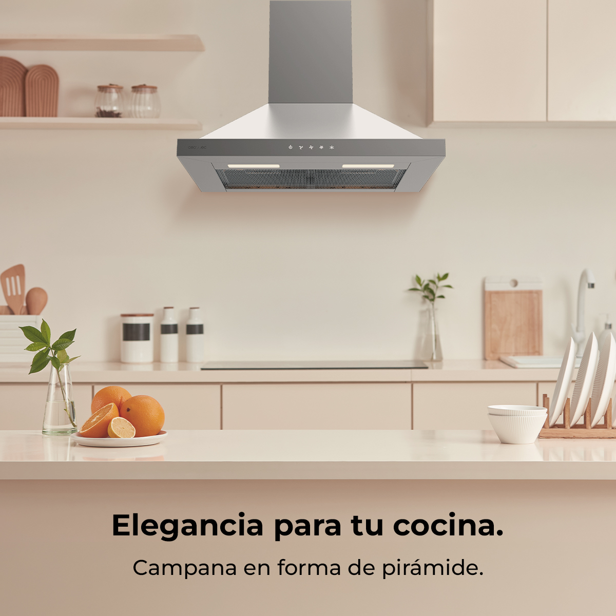 Cocina moderna con campana extractora plateada, gabinetes beiges, frutas cítricas en el mesón y texto en español.