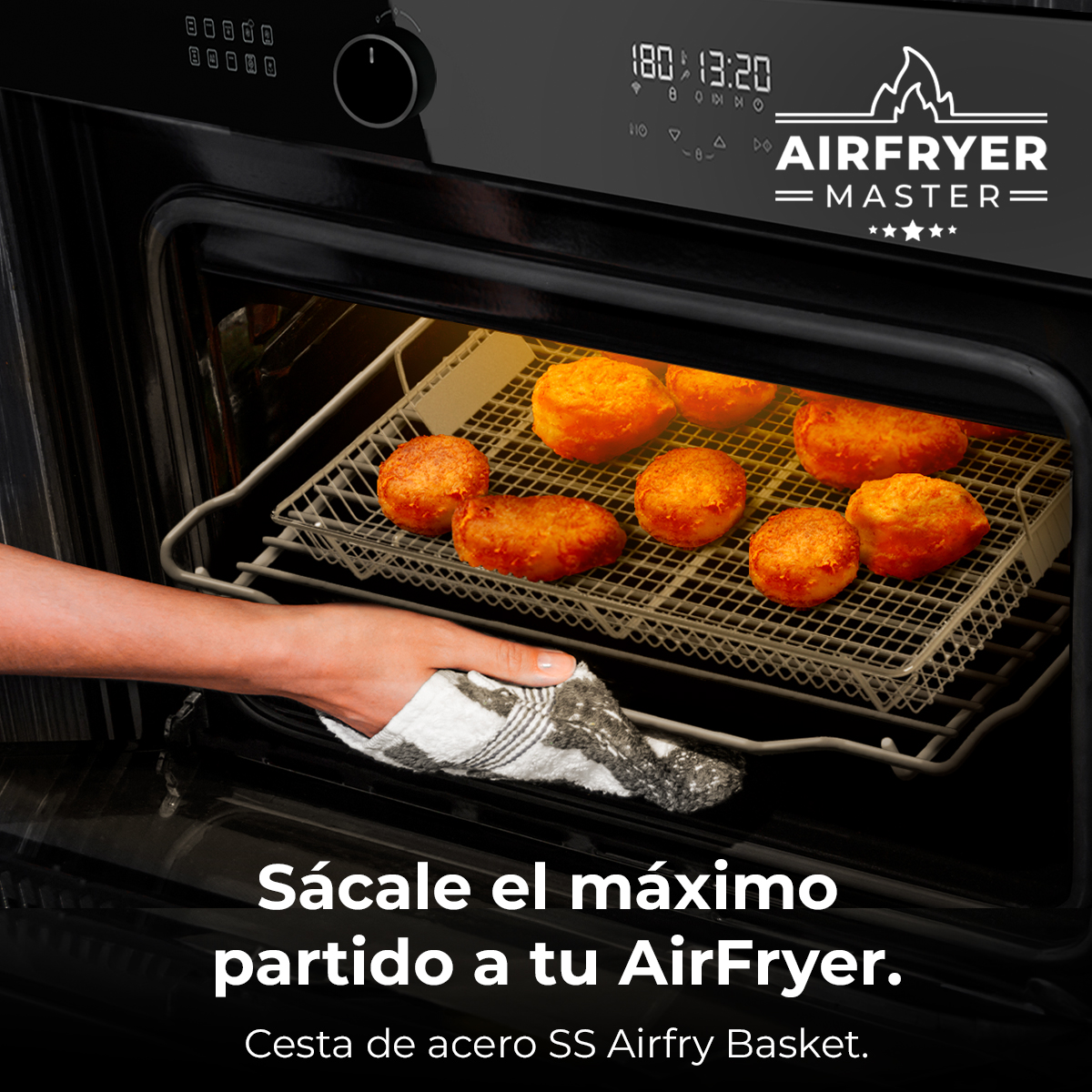 Mano con paño extrae rejilla con croquetas doradas de una freidora de aire negra.