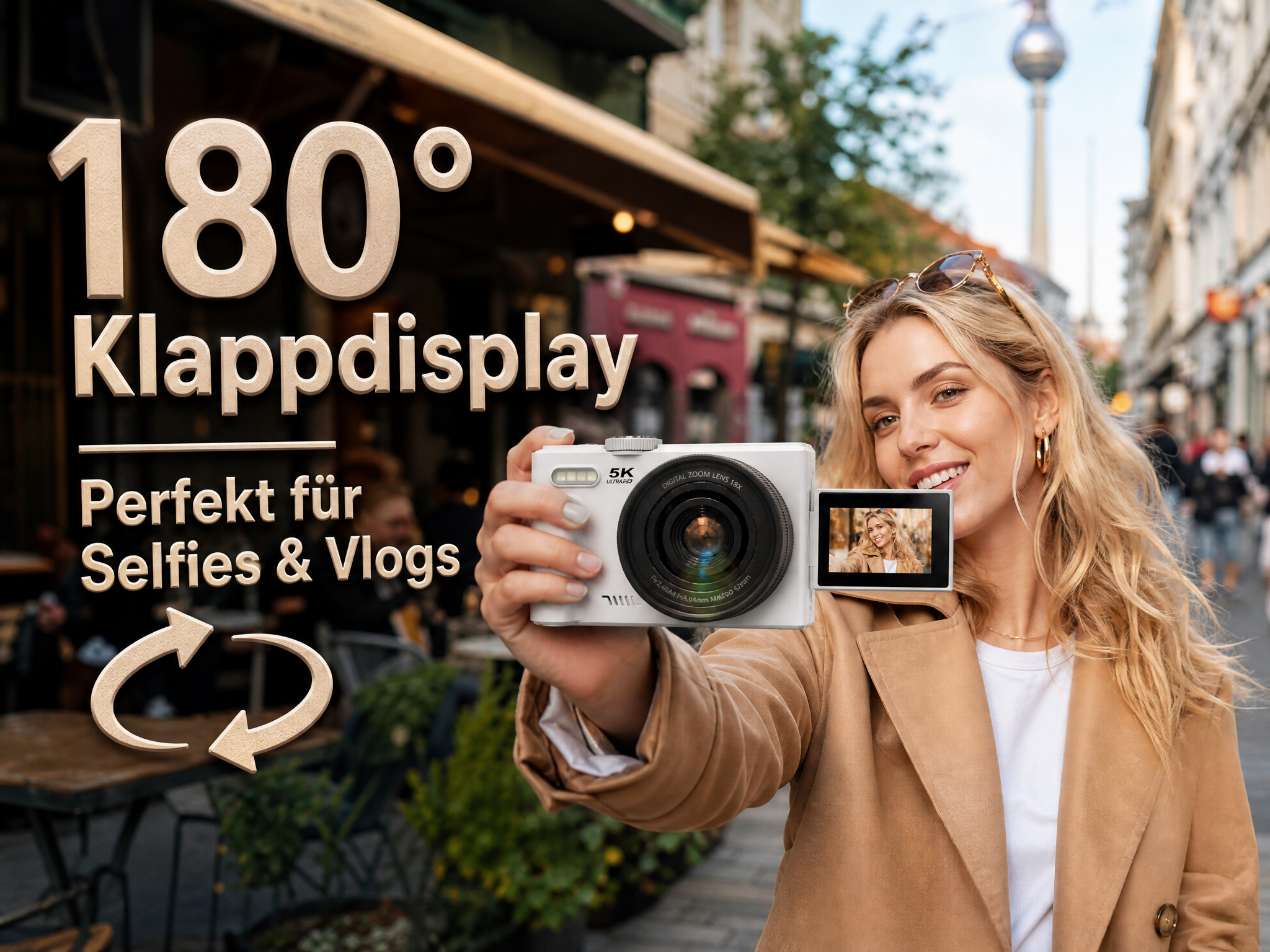 Eine junge Frau hält eine weiße Kompaktkamera mit Klappdisplay für ein Selfie in einer Stadt.