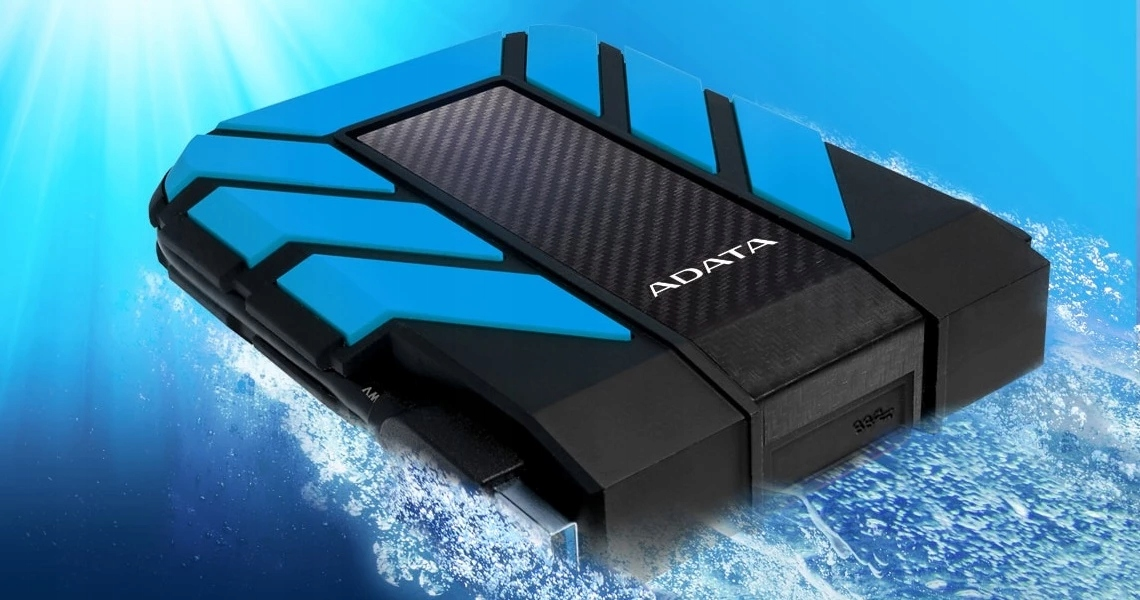A black and blue Adata external hard drive emerges from splashing blue water against a bright underwater background.