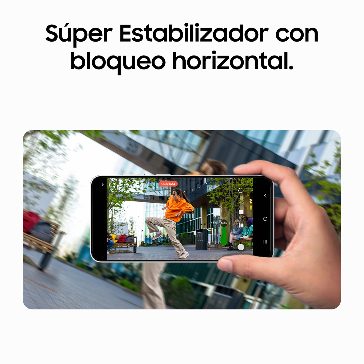 Una mano tiene uno smartphone che riprende una persona che balla in un parco.