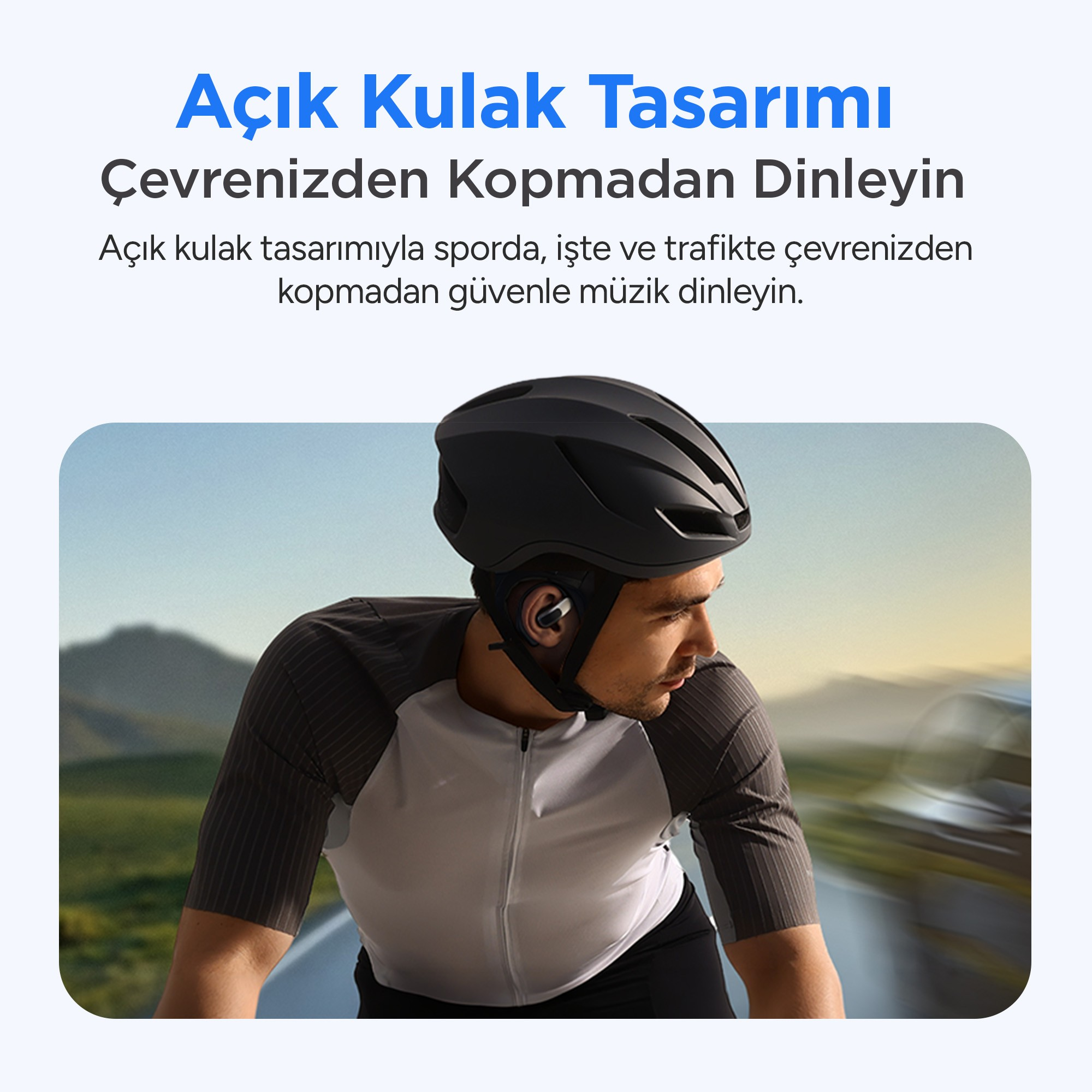 Açık kulak kulaklık ve siyah kask takan bisikletçi, dağ manzarasında açık havada bisiklet sürüyor.