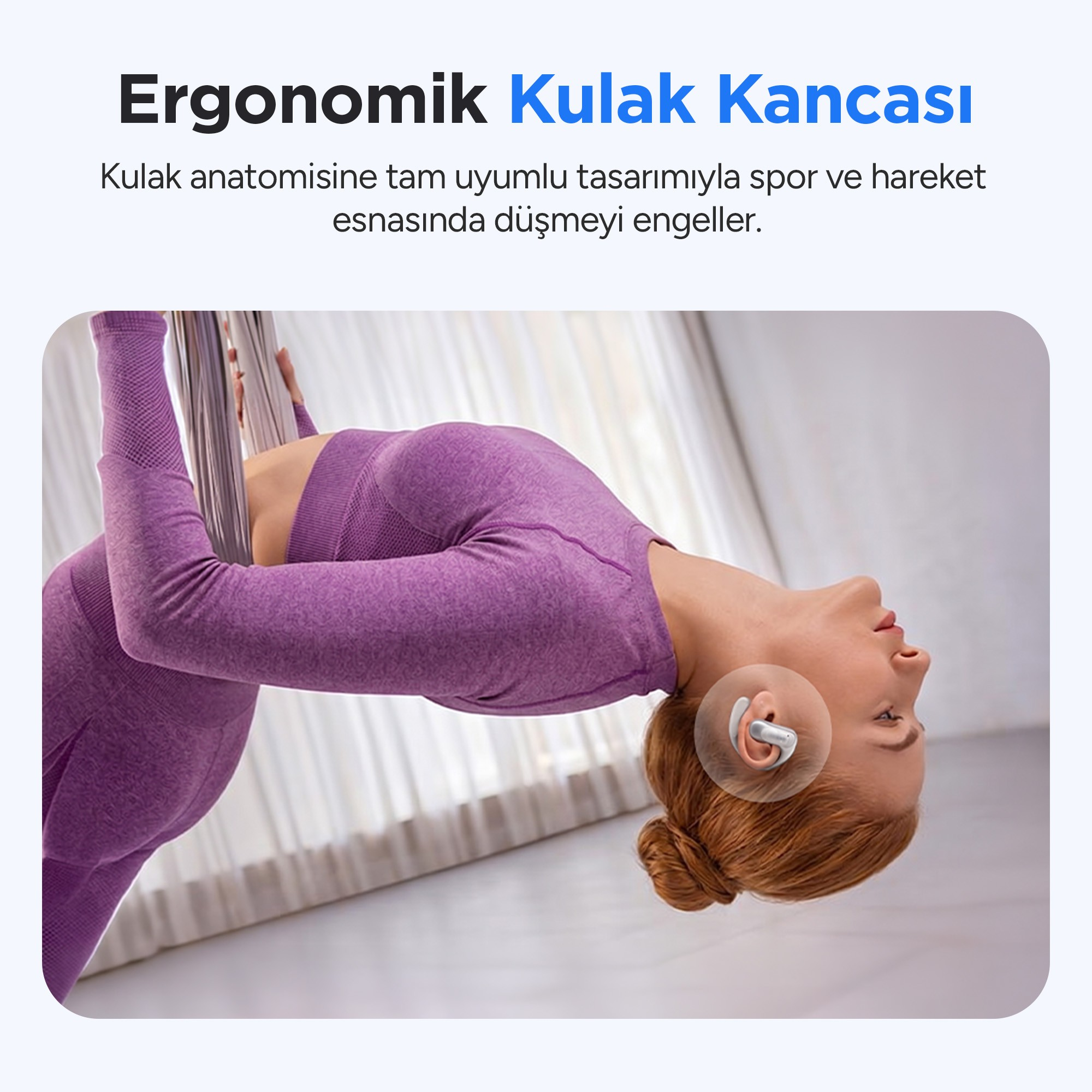 Mor yoga kıyafetli bir kadın, kablosuz kulaklıkla baş aşağı asılı duruyor.