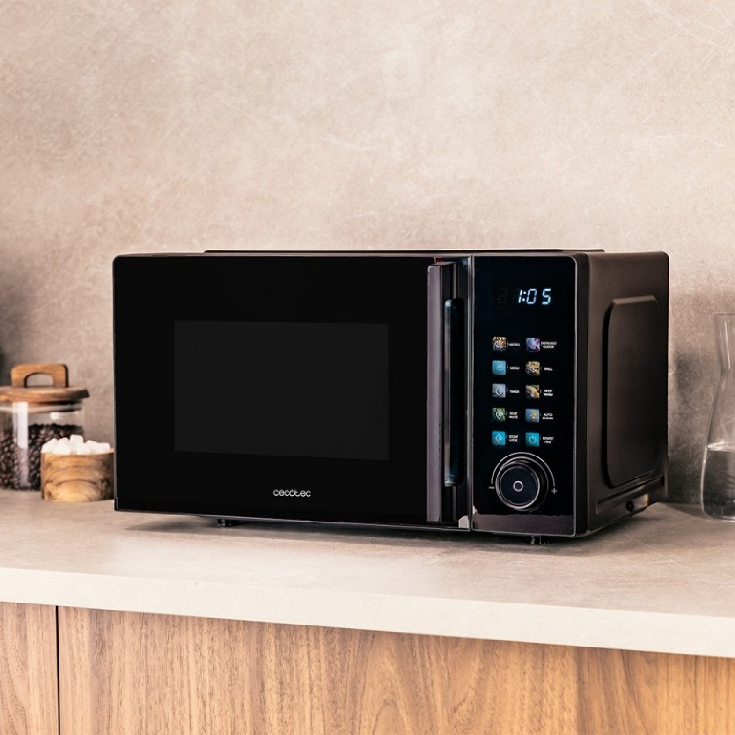 Un microondas moderno negro sobre la encimera con panel digital, junto a un tarro de café y agua.