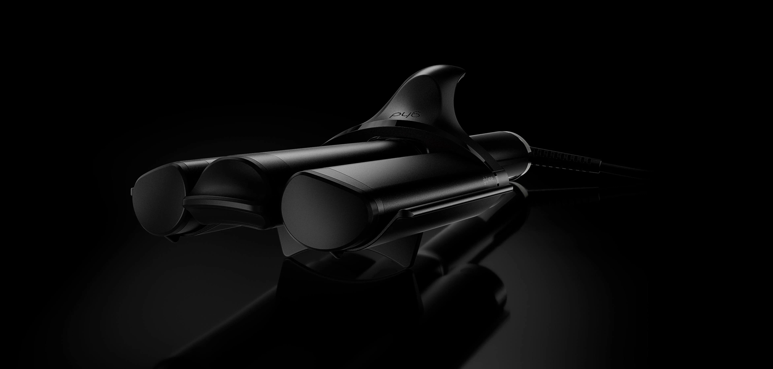 Un elegante arricciacapelli nero su una superficie scura riflettente con sfondo nero.