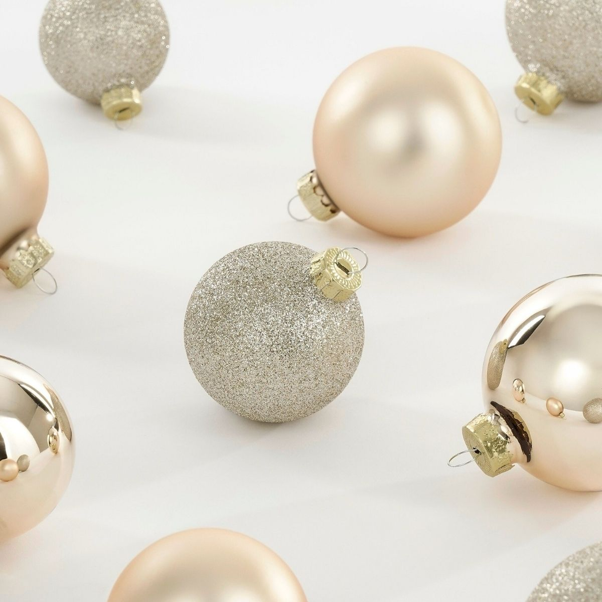 Shiny and glittery gold Christmas ornaments on a white background.
