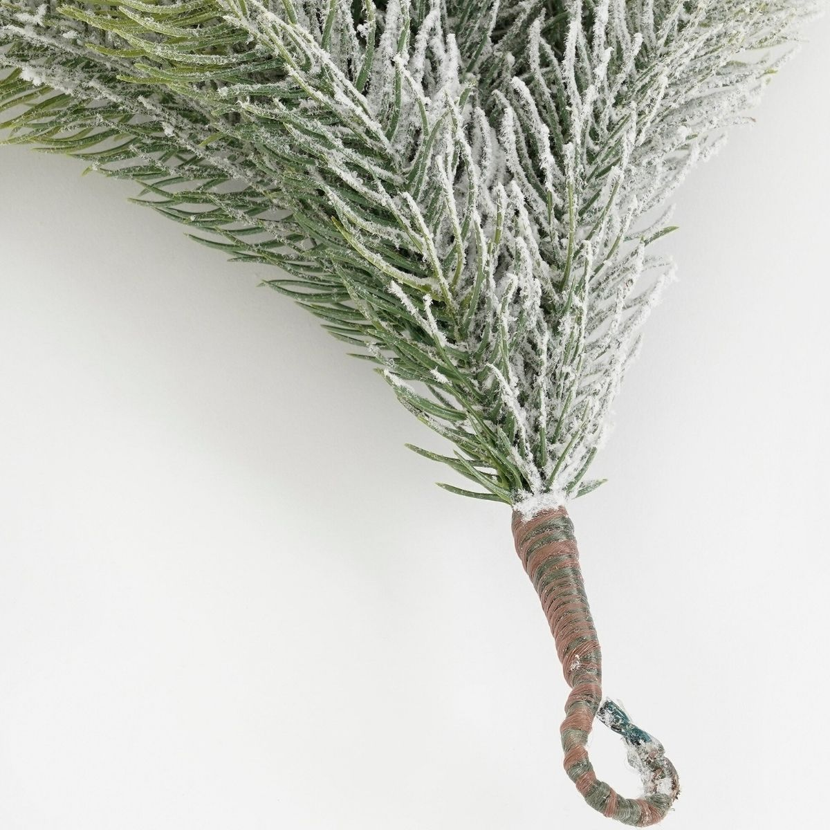 Une branche de pin givrée avec une tige enveloppée de marron sur fond blanc.