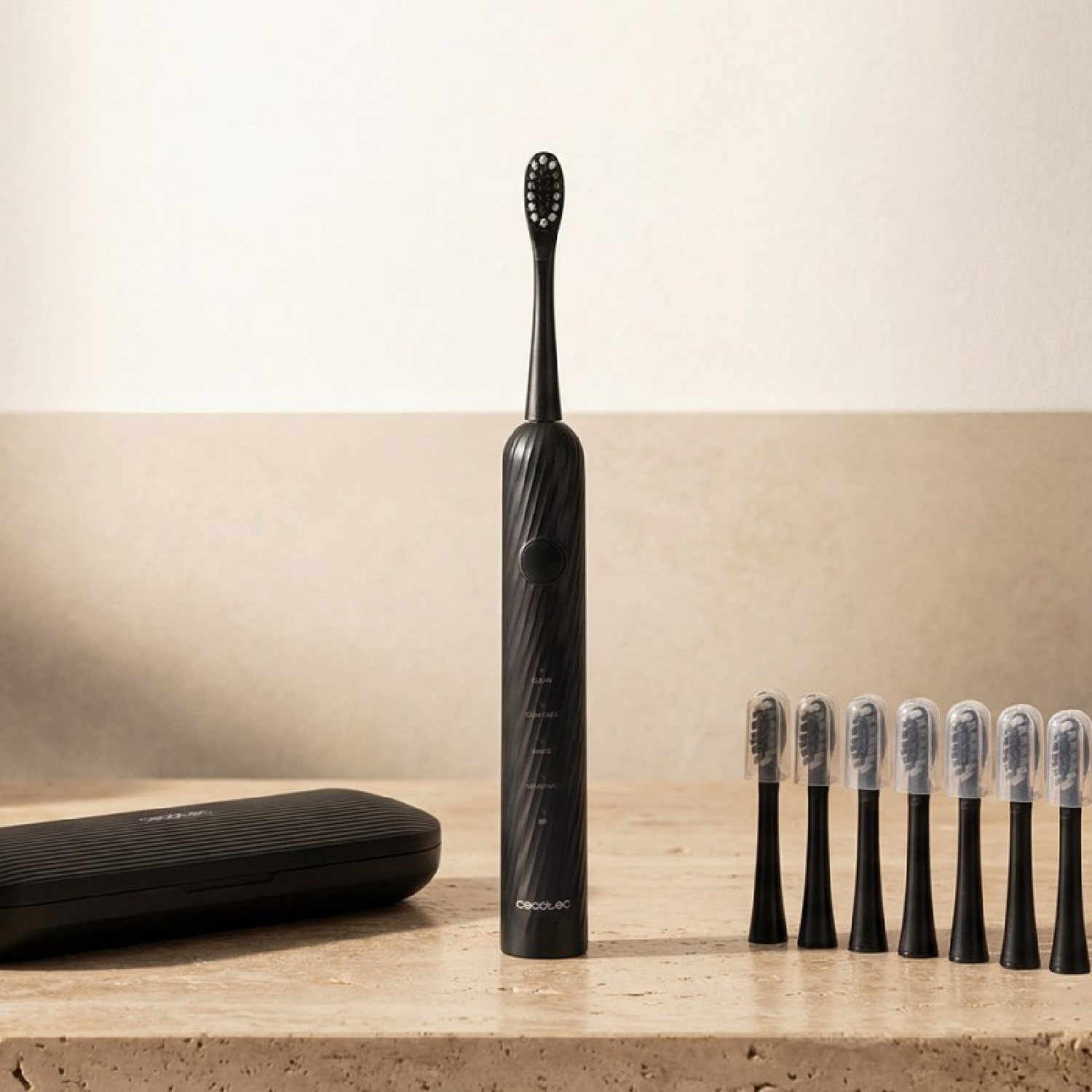 Un cepillo de dientes eléctrico negro sobre una superficie de madera con siete cabezales y un estuche.